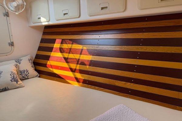 Cozy cabin interior of 2011 Reliance 44 sailboat with striped wood paneling and pillows.