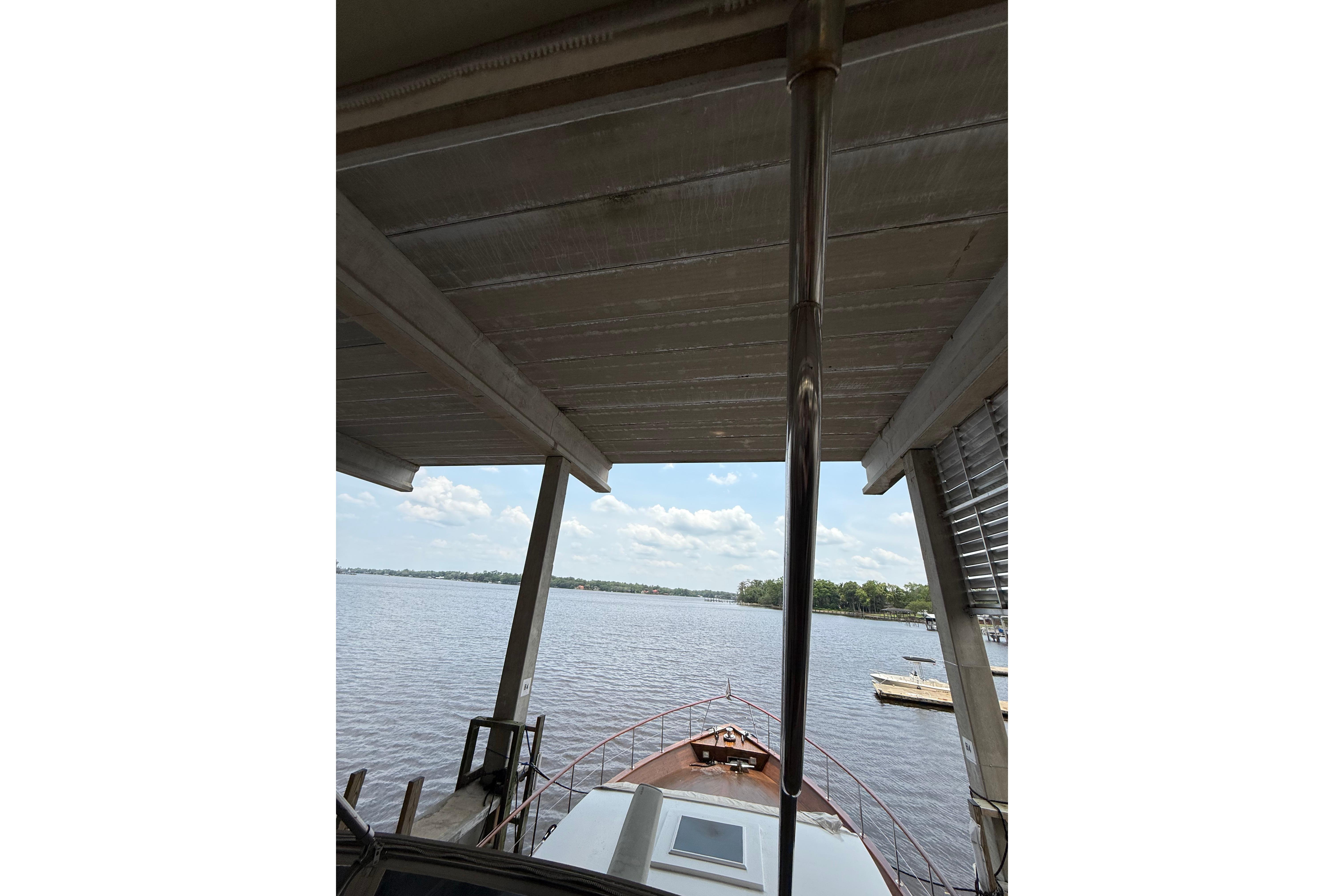 1974 Pacemaker Cockpit Motoryacht docked under a covered structure, overlooking a serene lake.