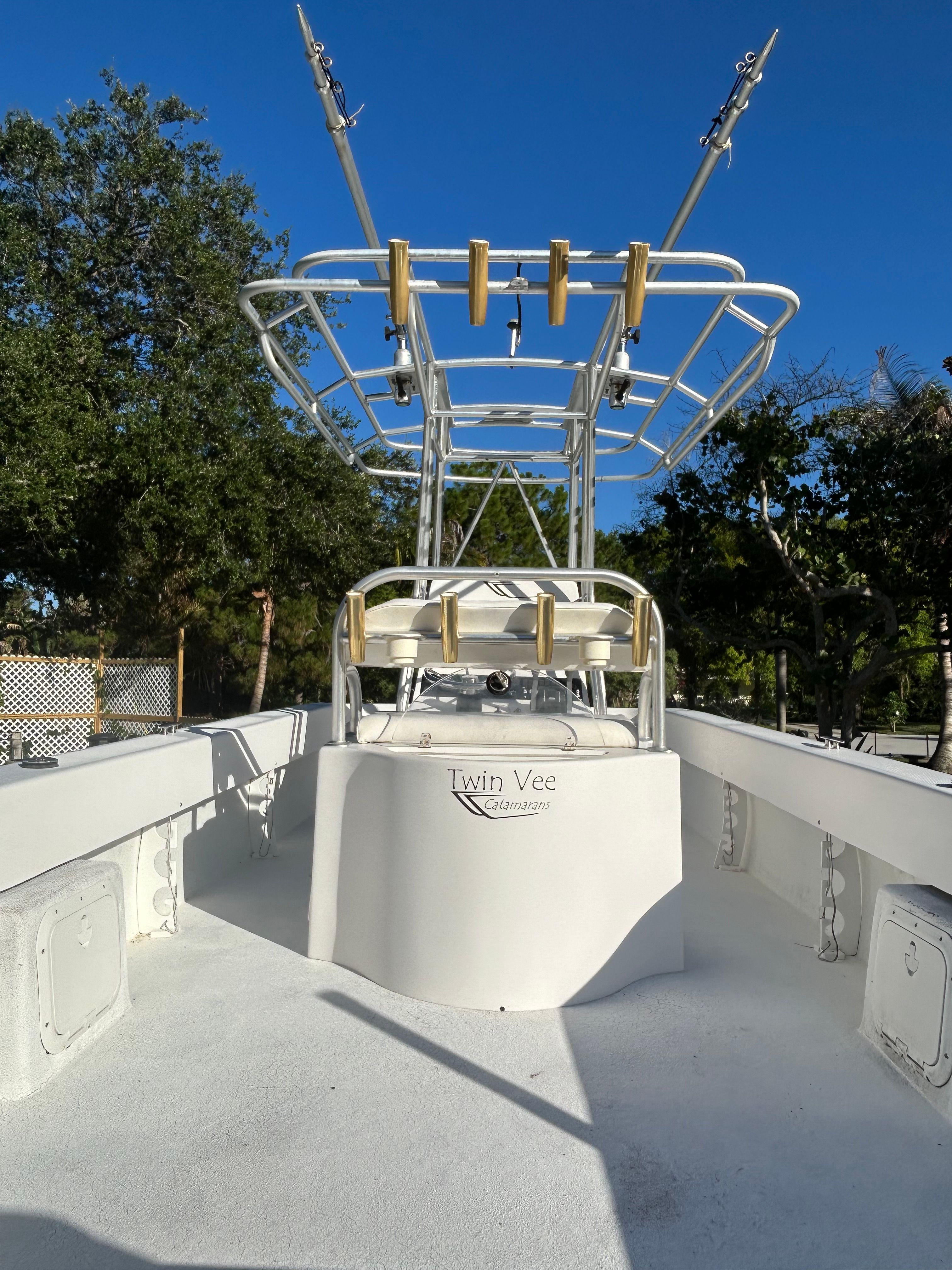 A 2007 Twin Vee 26 Center Console boat with T-top and fishing rod holders, surrounded by trees.