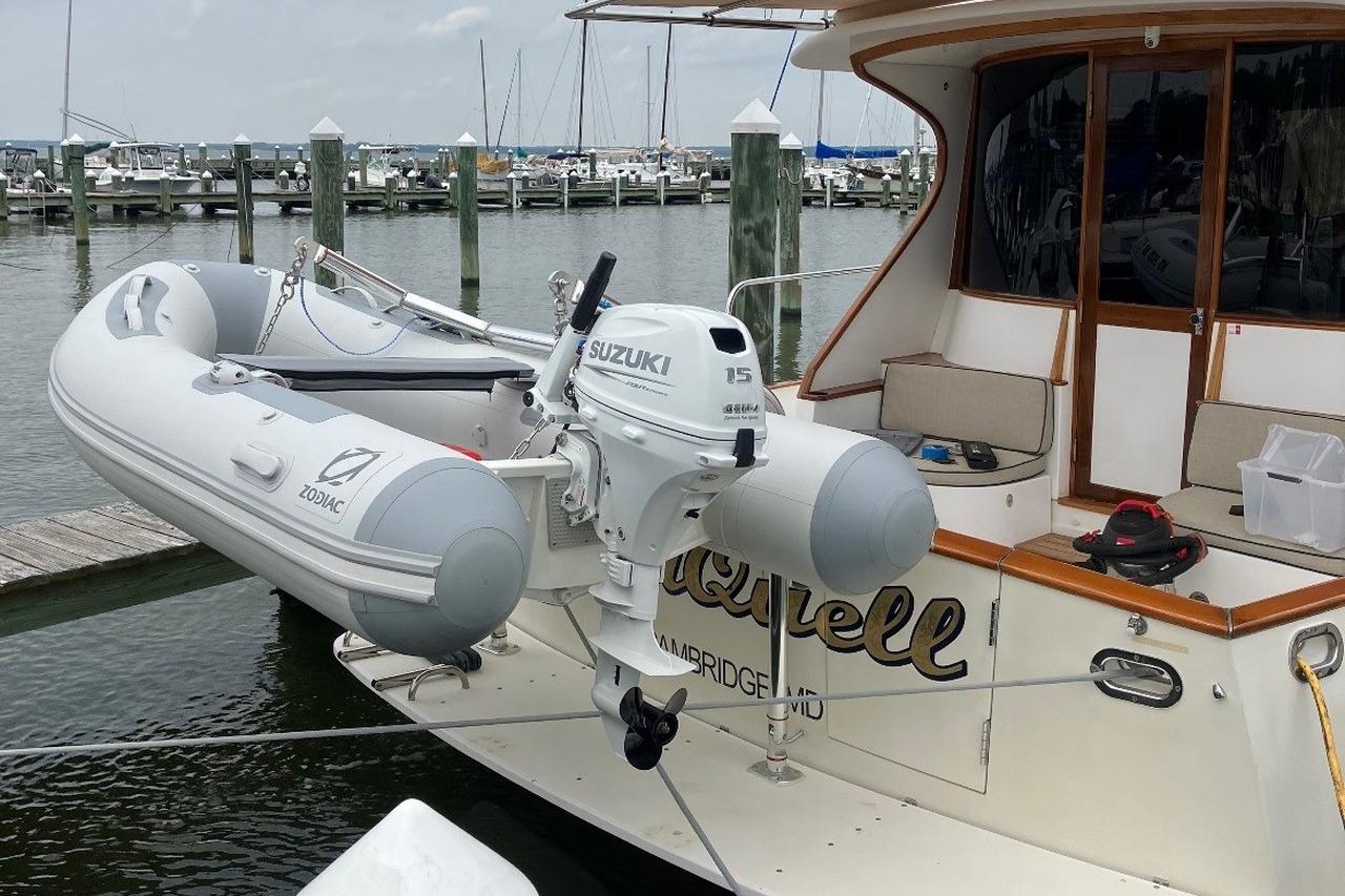 A Zodiac inflatable boat with Suzuki outboard motor docked at a marina.