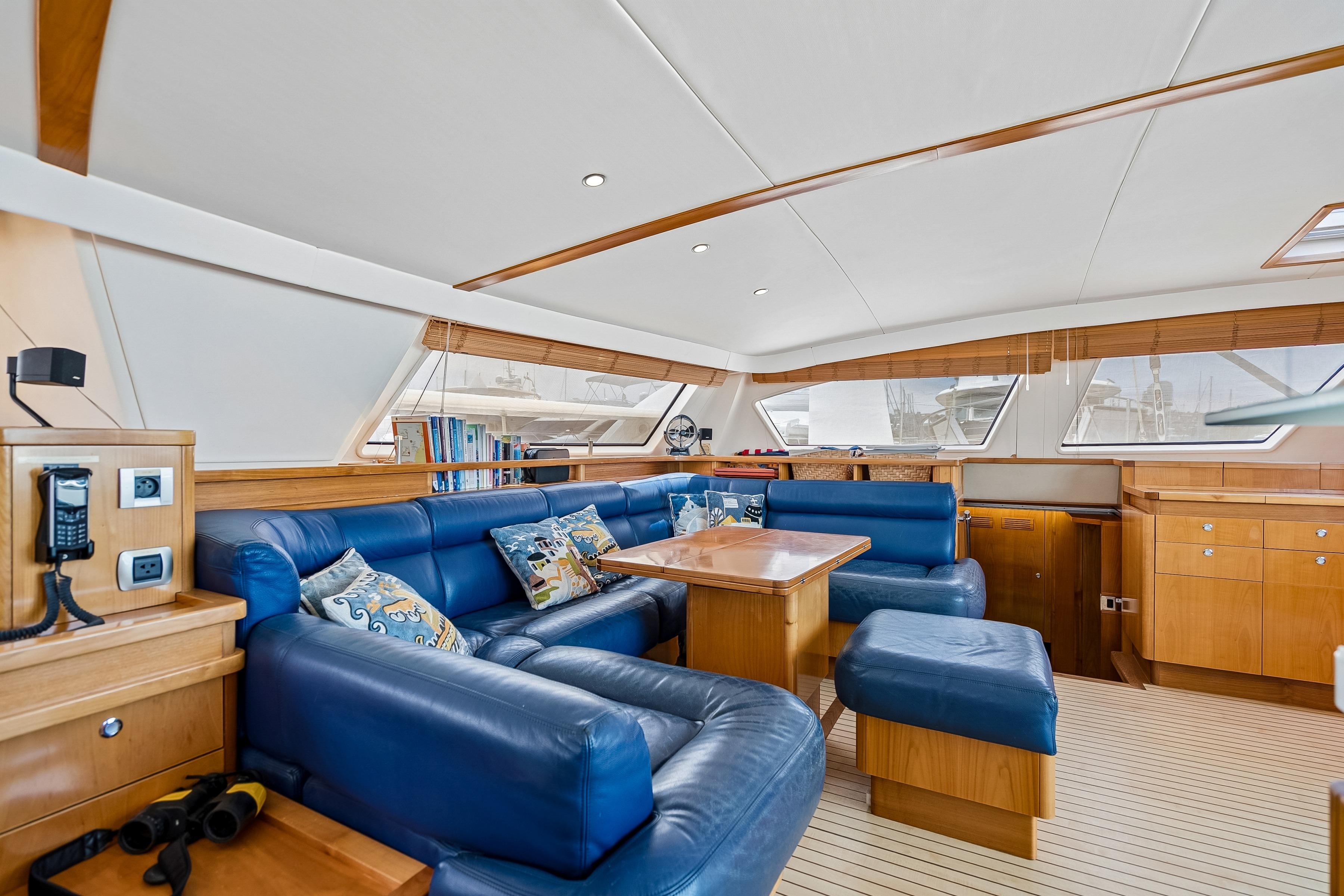 Luxurious interior of 2009 Catana 65 yacht with blue leather seating and wooden accents.