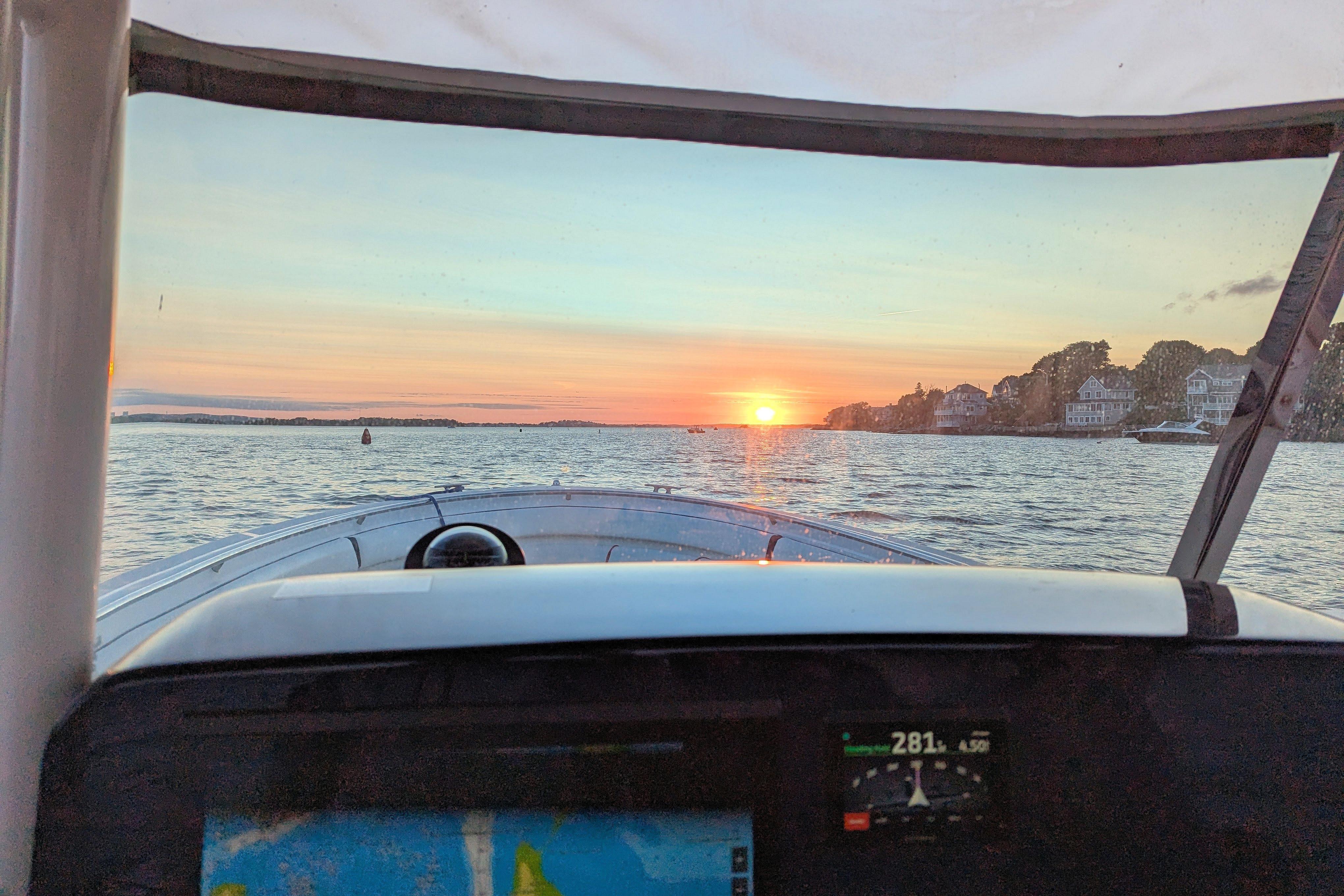 2013 Pursuit ST 310 Sport boat navigating at sunset, scenic waterfront view.