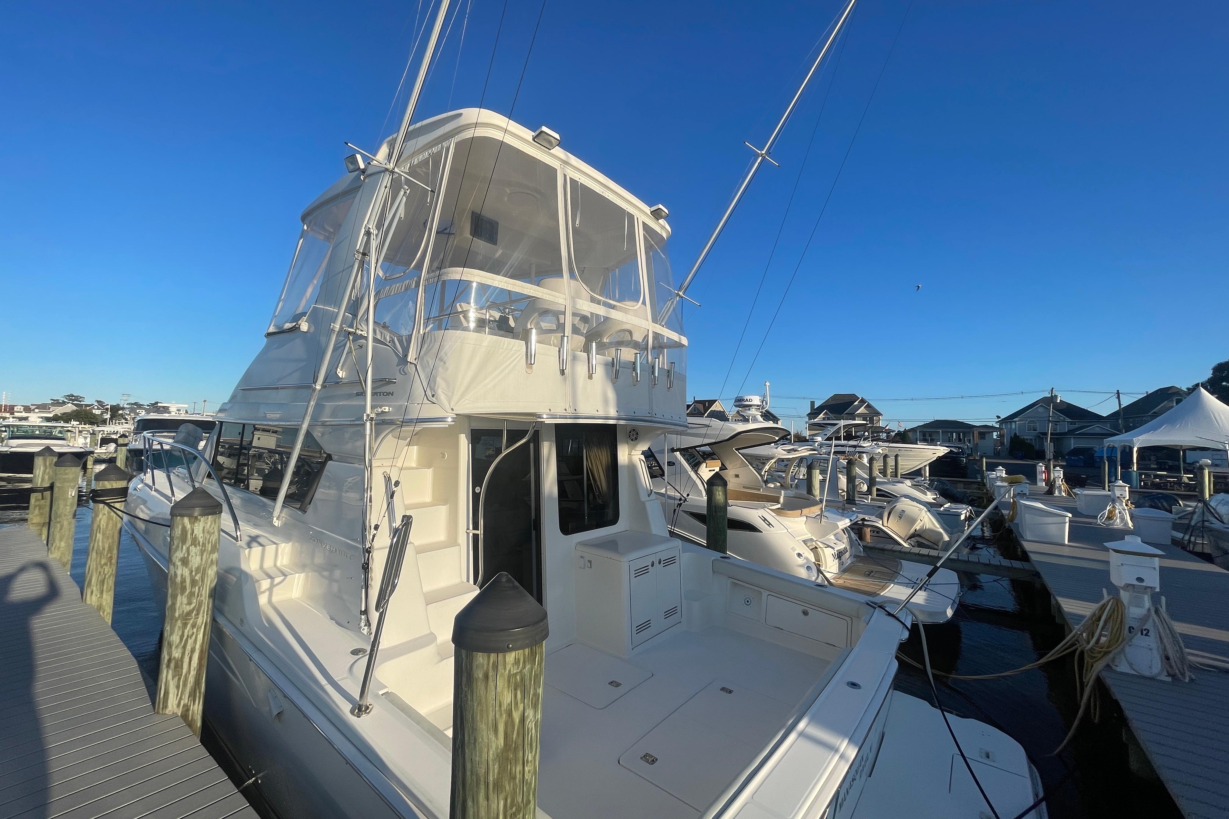 2006 Silverton 42 Convertible yacht docked at marina under clear blue sky.