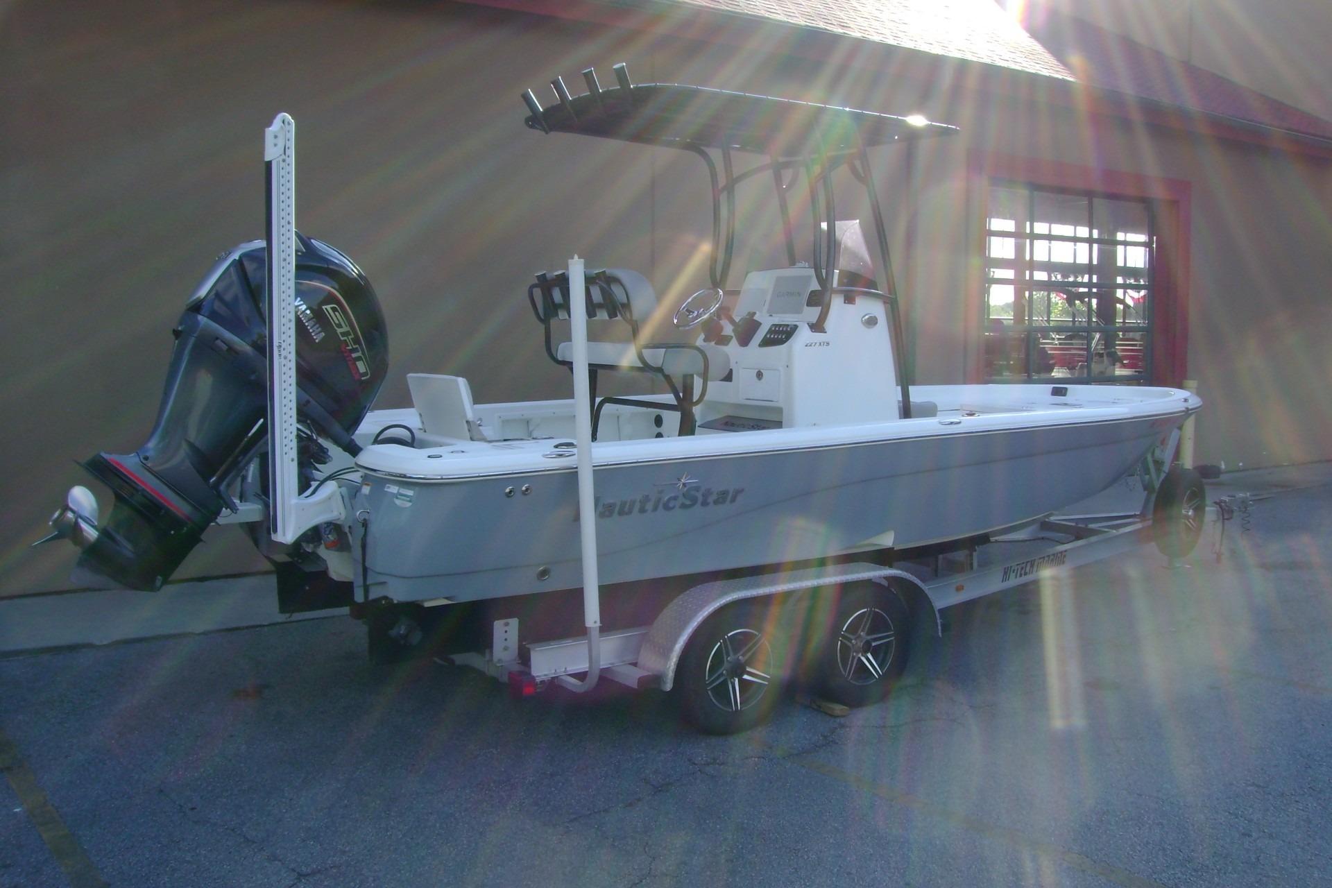 2022 NauticStar 227 XTS boat on trailer, parked outdoors with sunlight reflections.