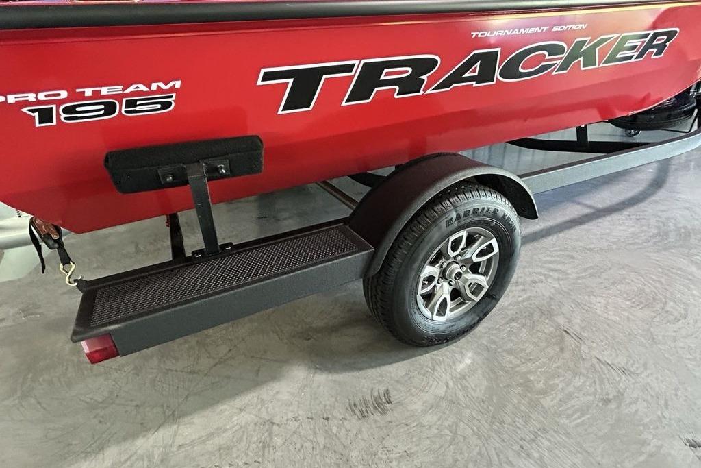 Red 2026 Tracker Pro Team 195 boat on trailer, showcasing logo and wheel detail.