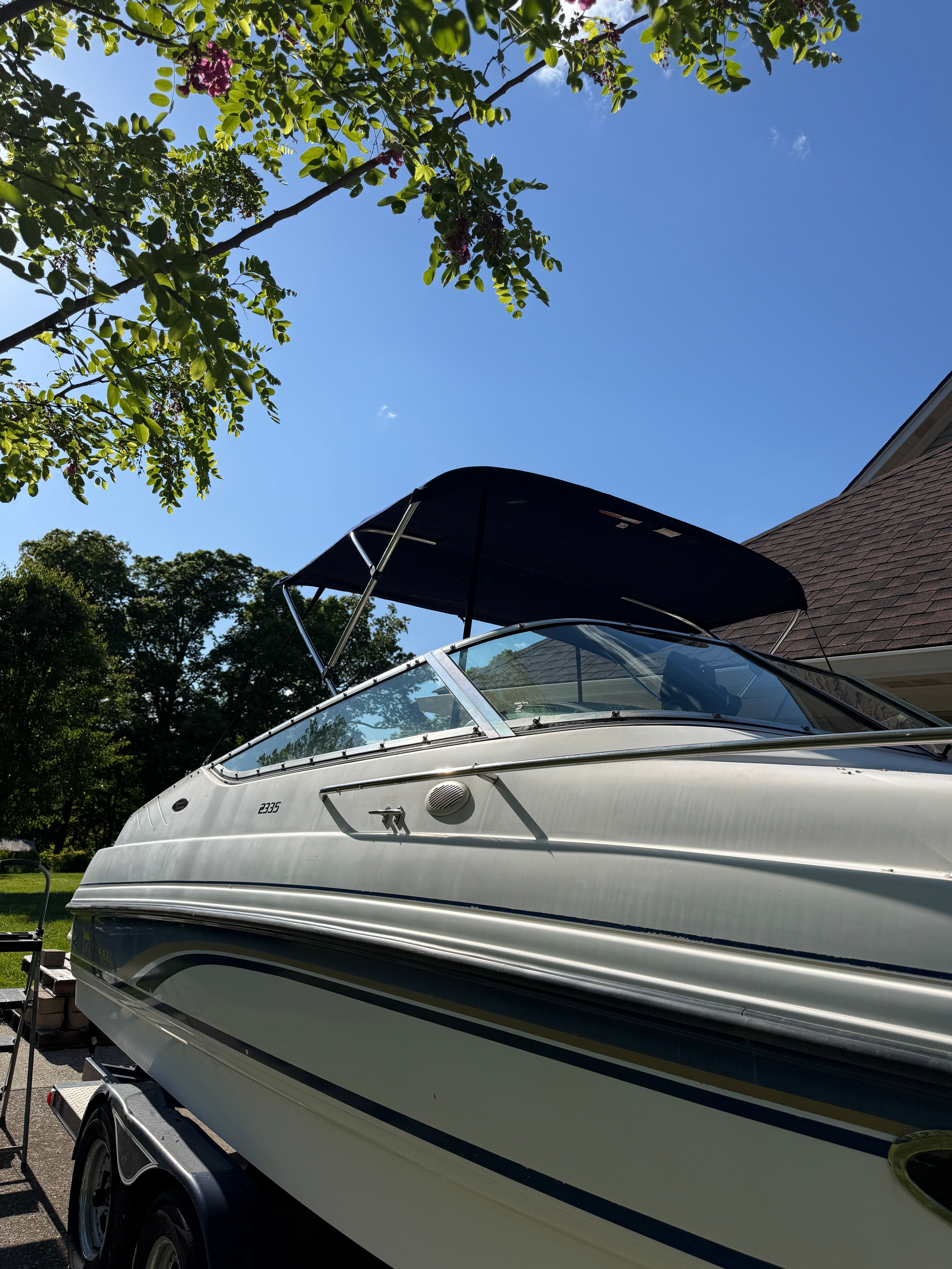 1999 Custom 2335 Cuddy Cabin boat on trailer, sunny day.