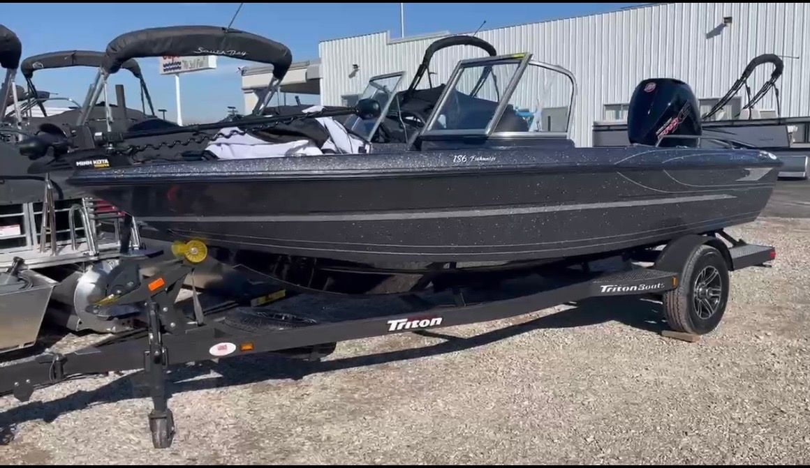 A 2023 Triton 186 Fishunter on a trailer, parked on a gravel lot.