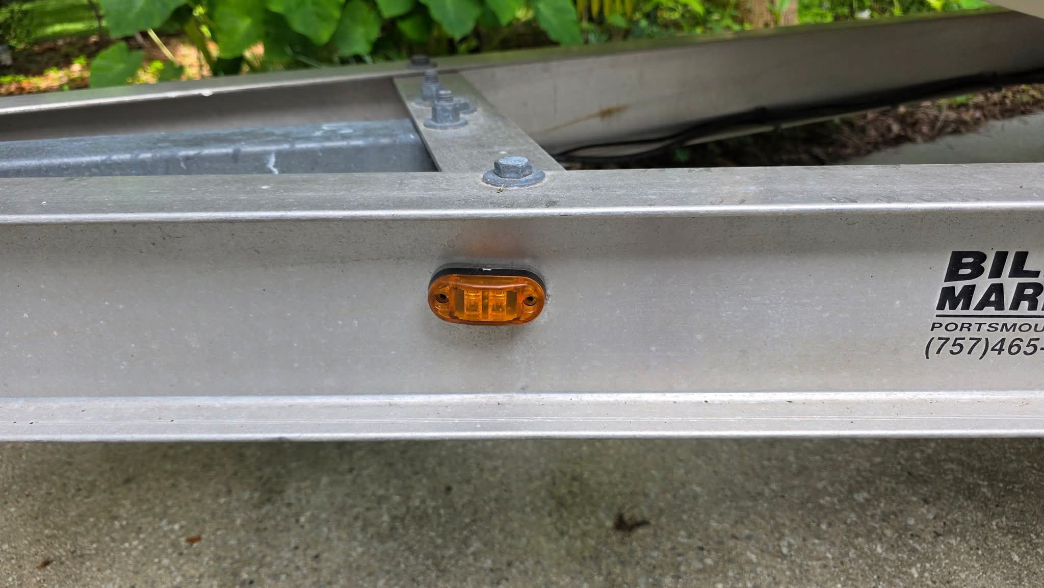Close-up of a boat trailer with an orange light and bolts.