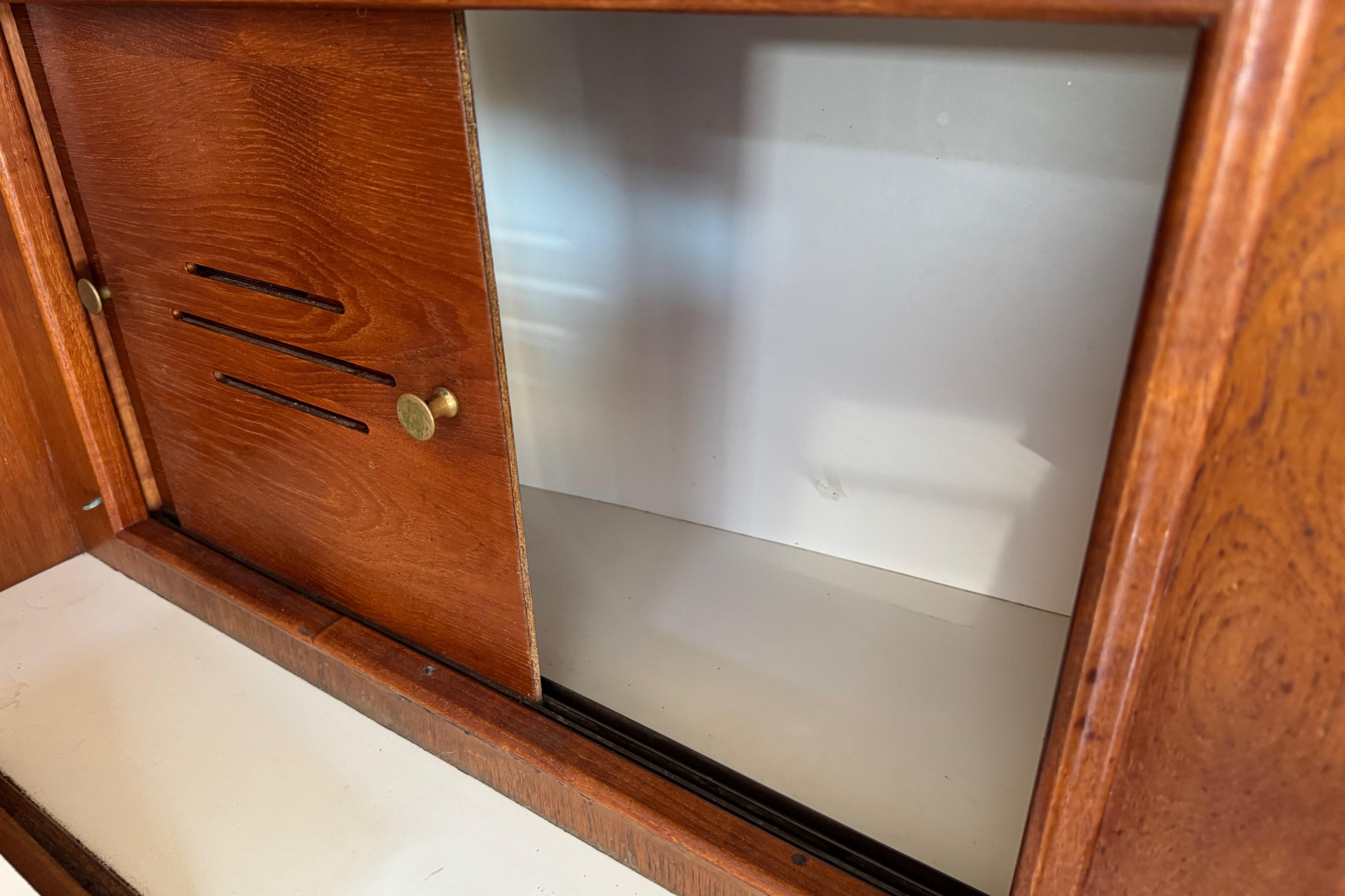 Wooden cabinet interior on a 1989 Cape Dory 30 Motorsailer, featuring sliding doors.
