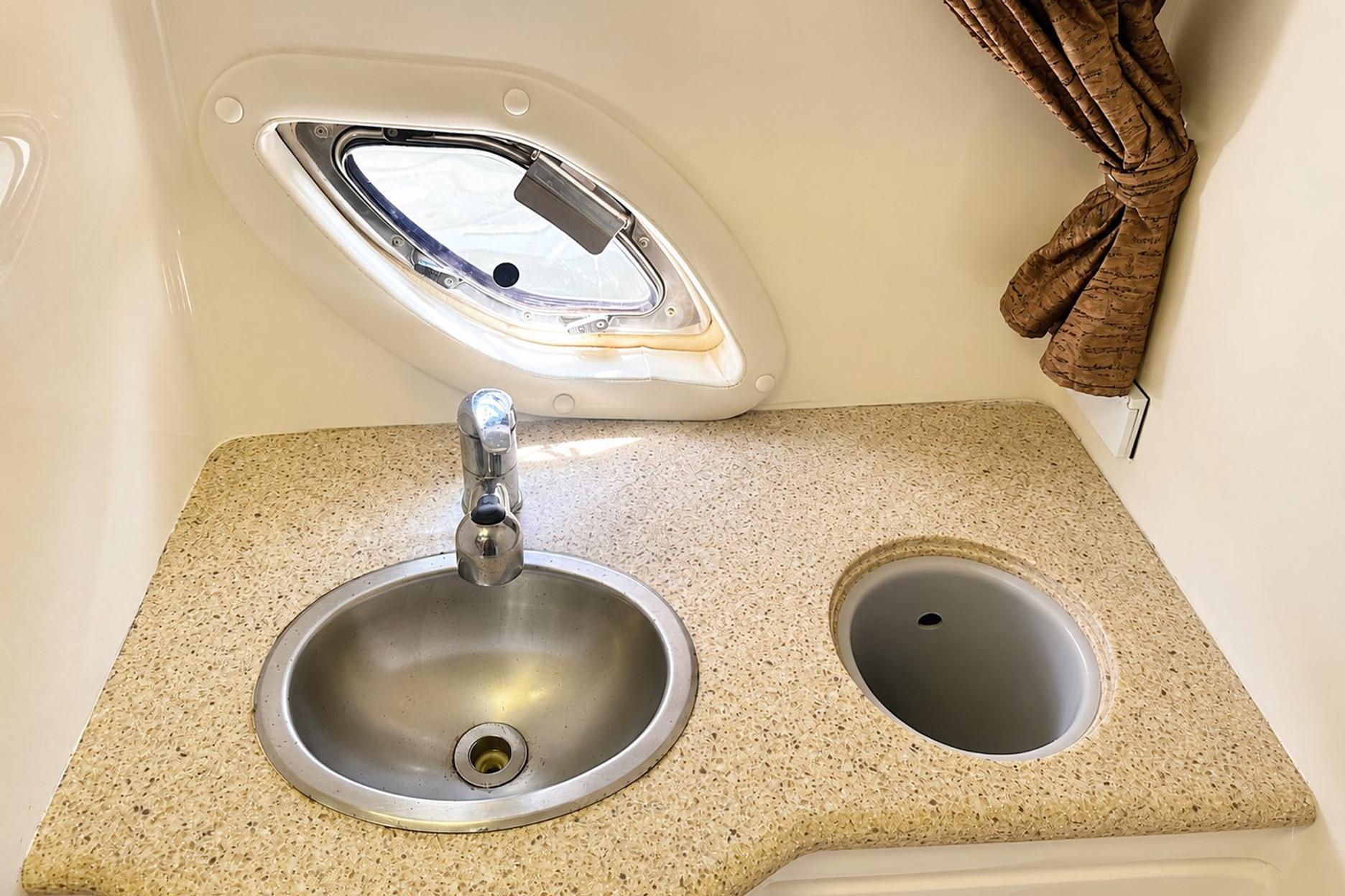 2012 Rinker 310 Express Cruiser LE bathroom sink with porthole and countertop.