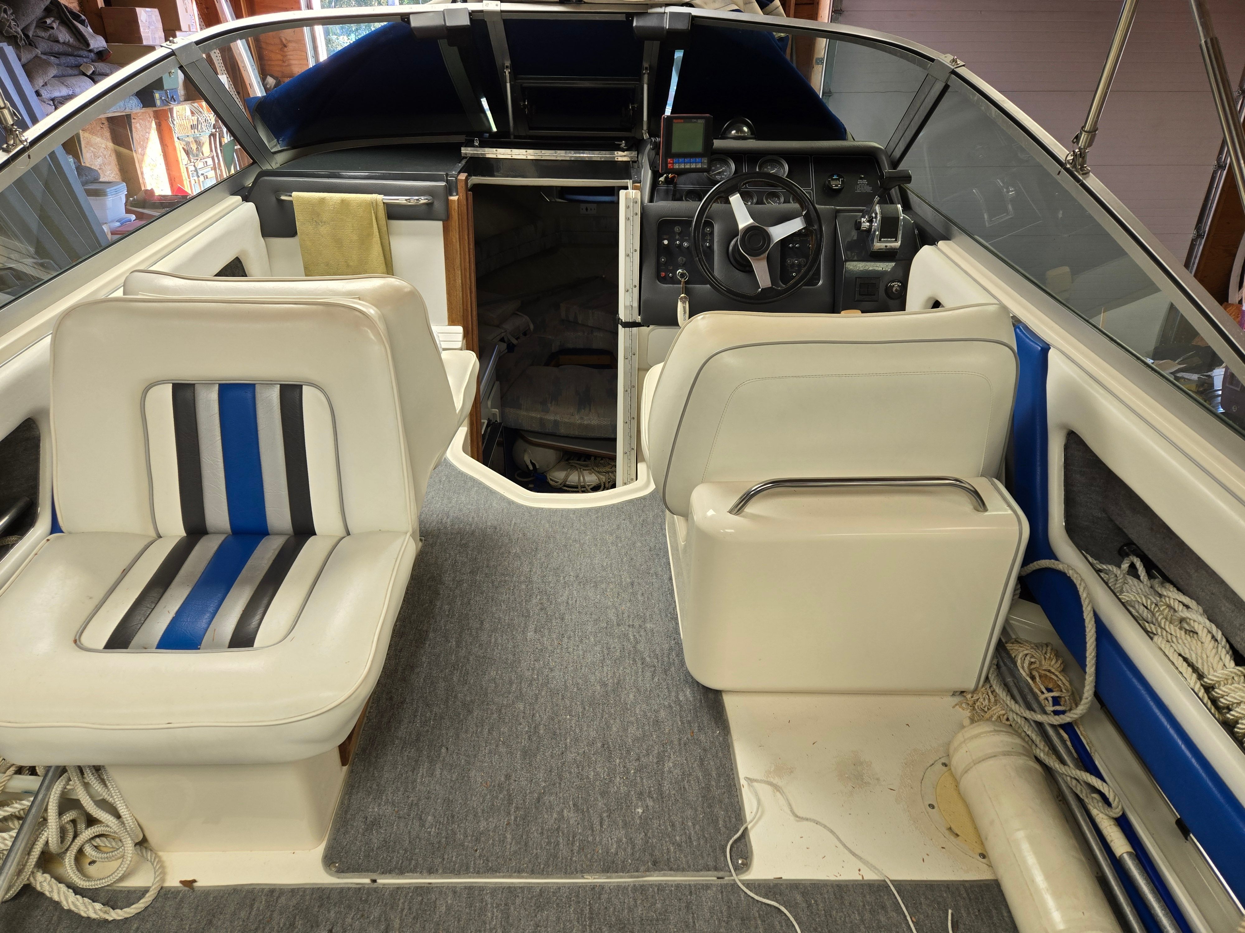 Interior of a 1991 Sea Ray 250 Weekender with white seats and blue accents.