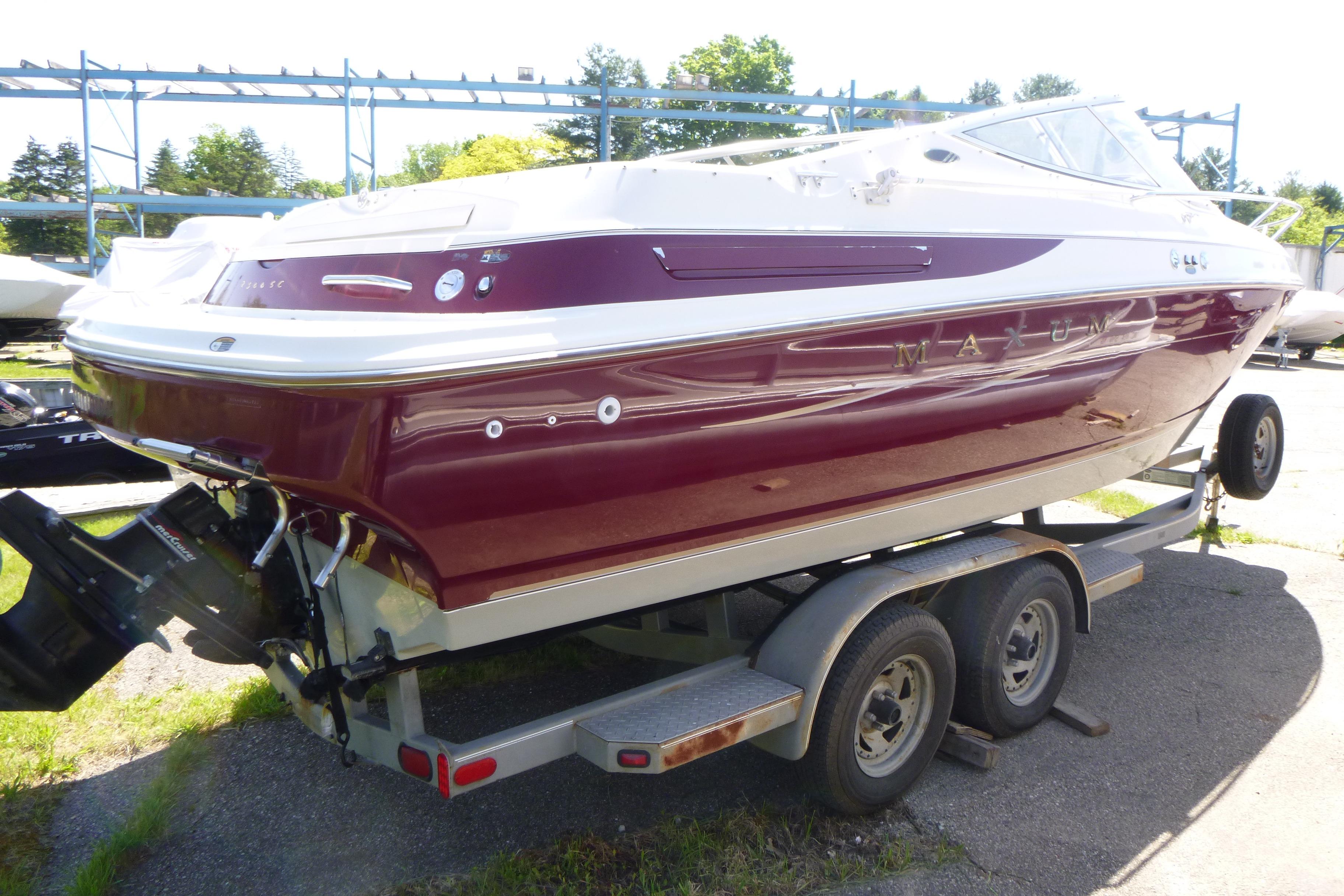 1998 Maxum 2300 SC boat on trailer, maroon and white exterior, parked outdoors.