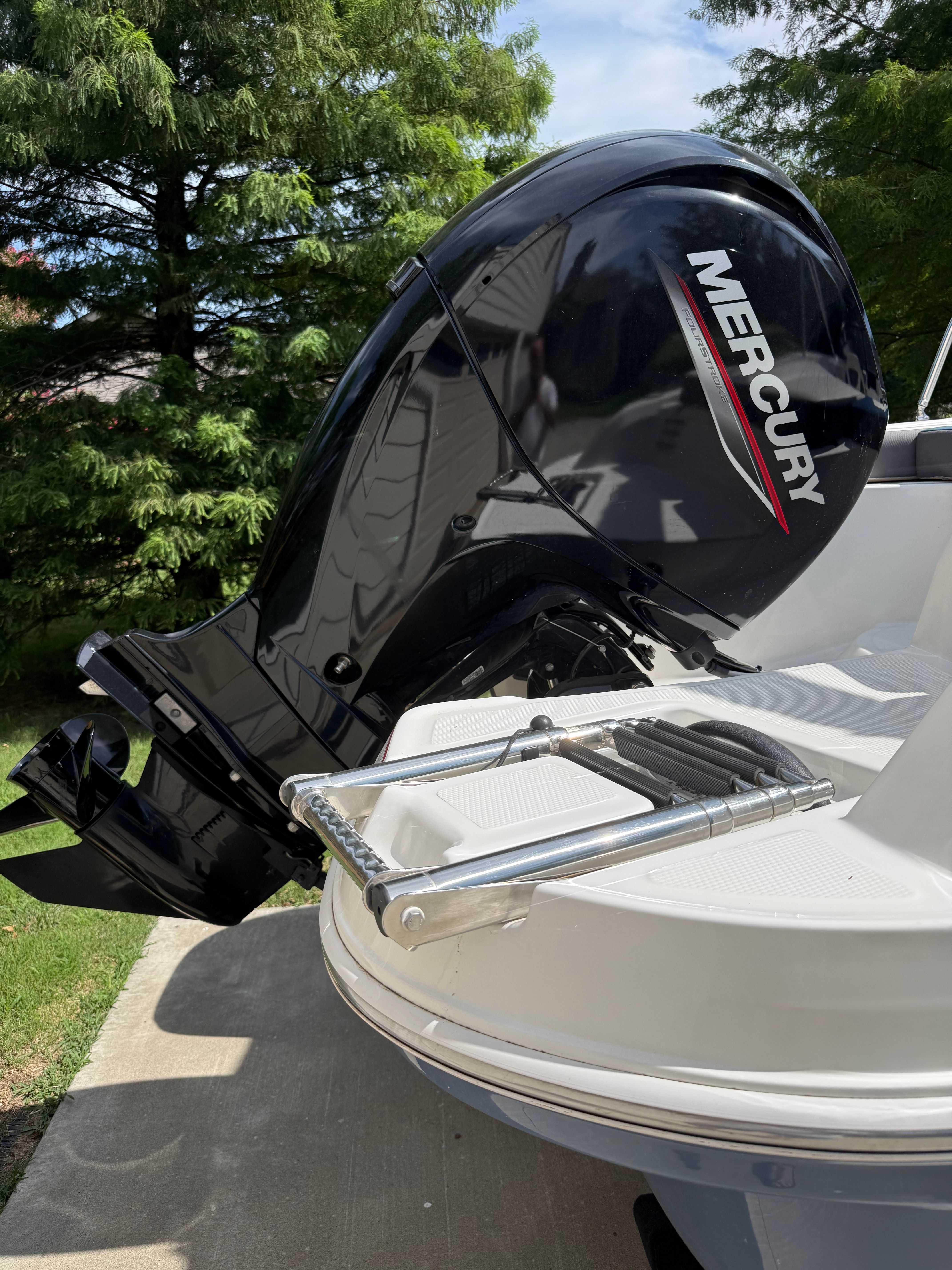 A Mercury outboard motor on a white boat with a swim ladder.