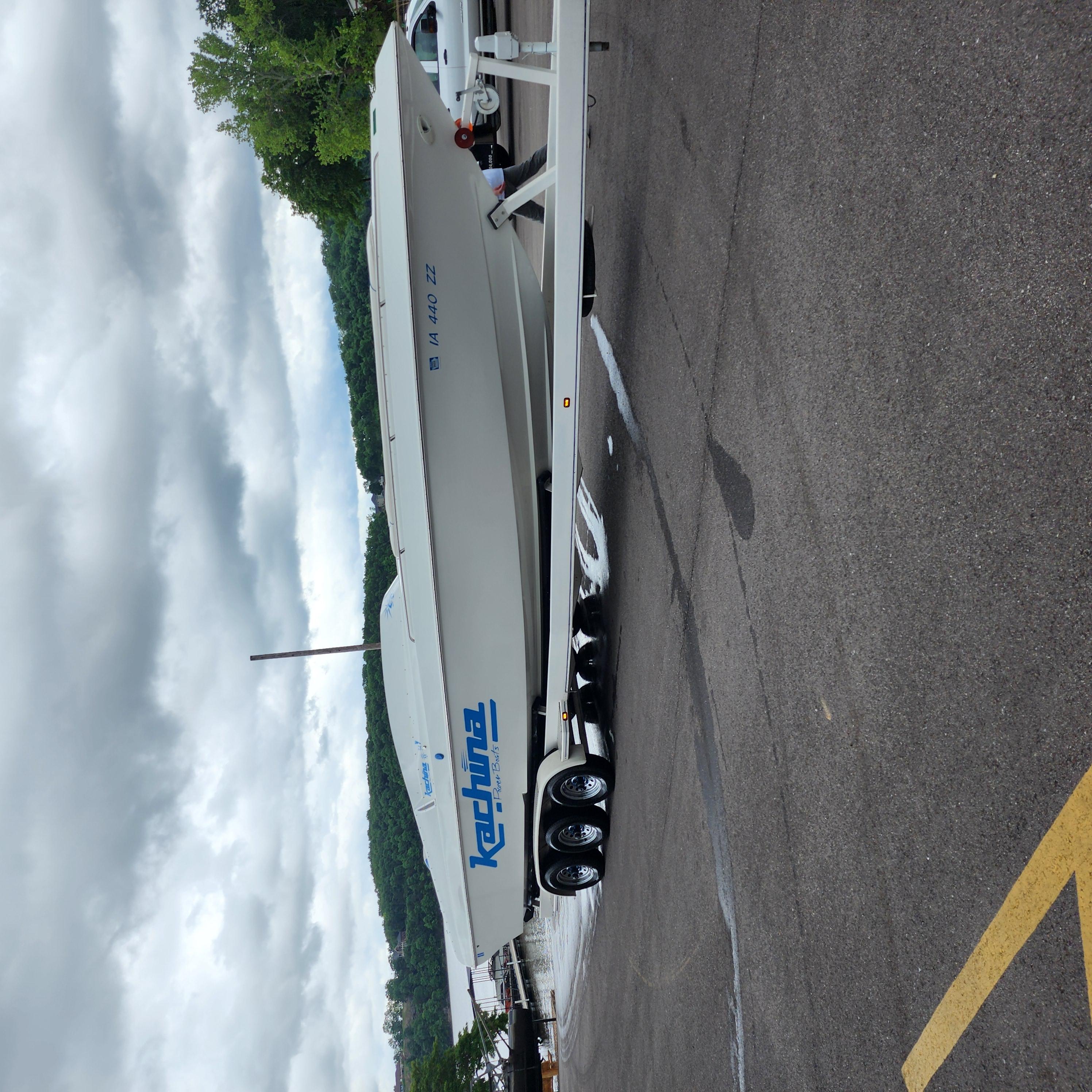 2005 Kachina Bolero boat on trailer in parking lot, cloudy sky background.
