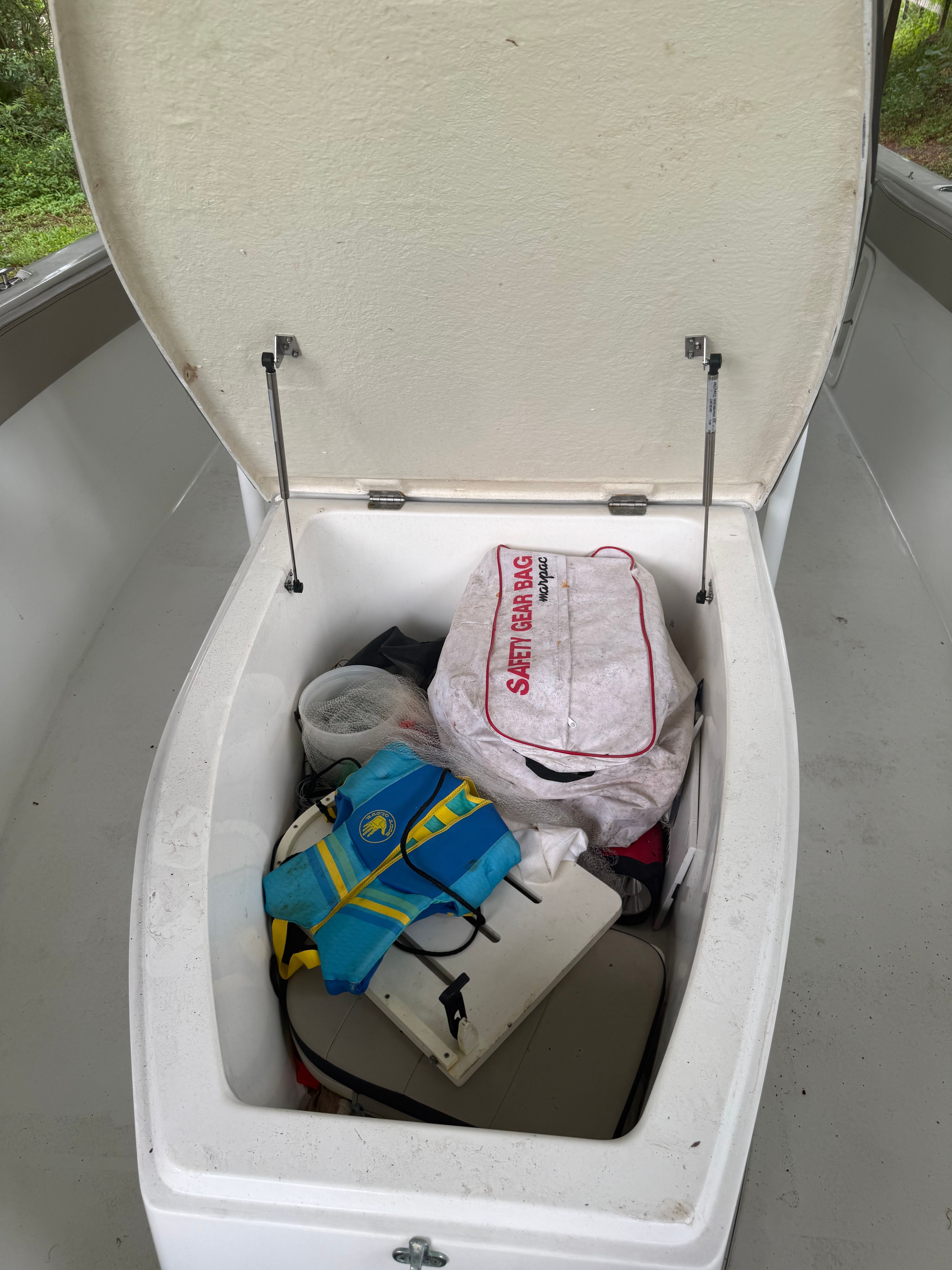 Boat storage compartment with life jacket and bags.