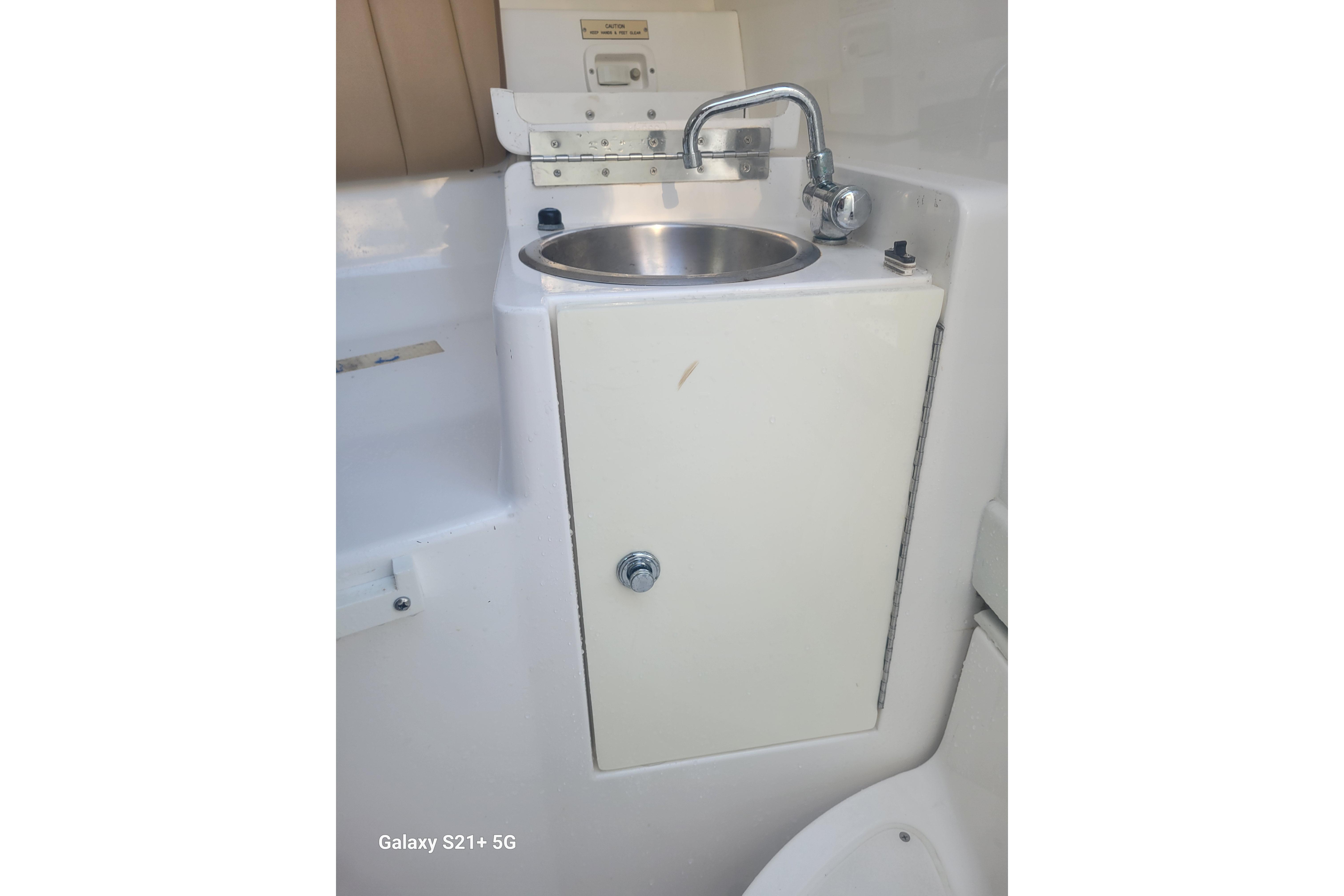 2005 Intrepid 323 Cuddy boat sink with faucet and storage cabinet.