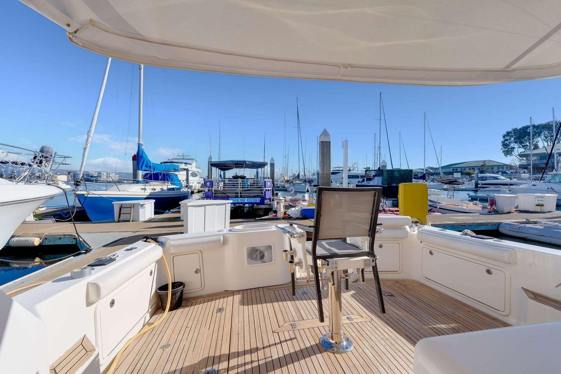 2004 Riviera Convertible yacht deck with marina view, featuring seating and fishing equipment.