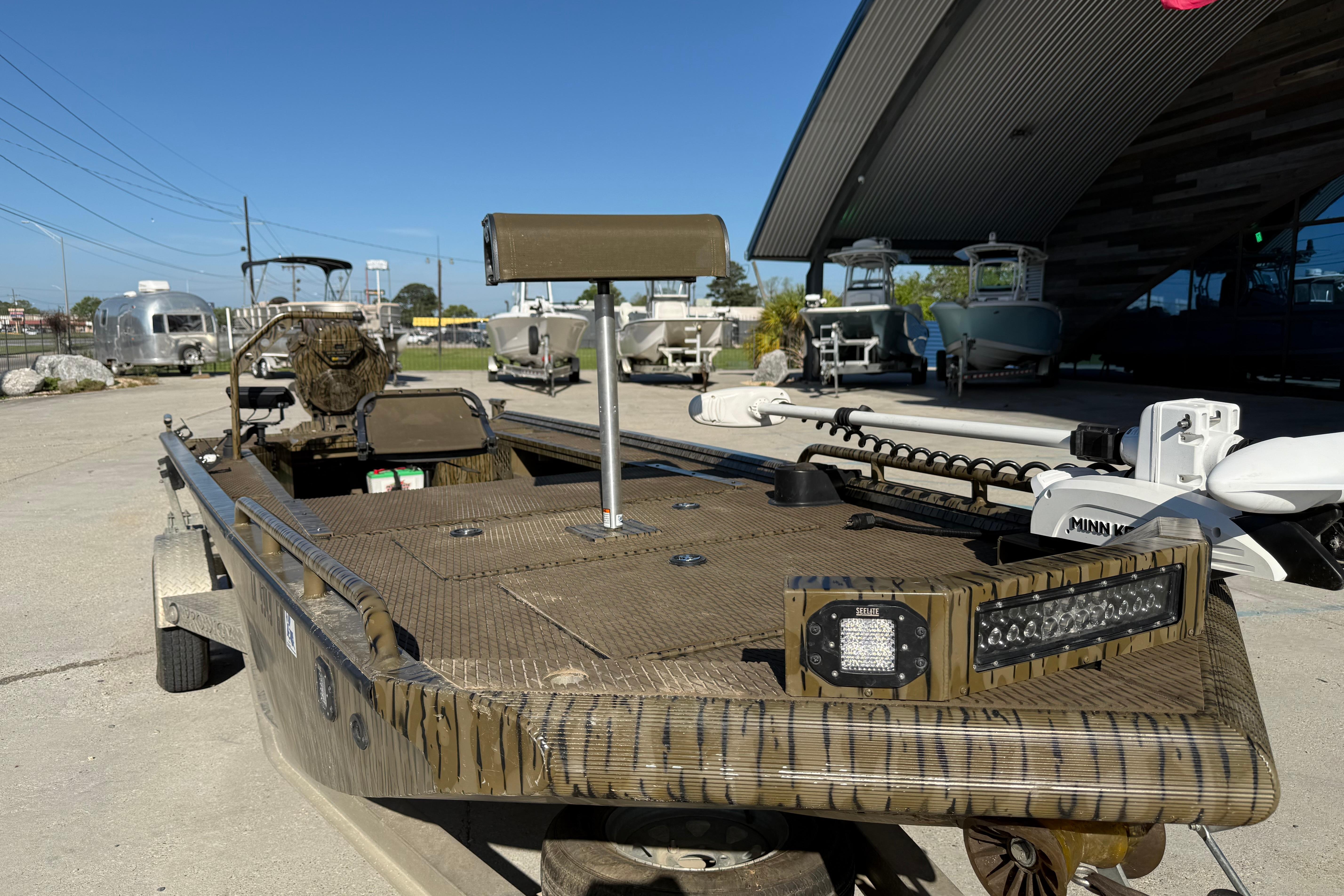 2022 Prodigy 1854 boat with camouflage design, parked outdoors near other boats.