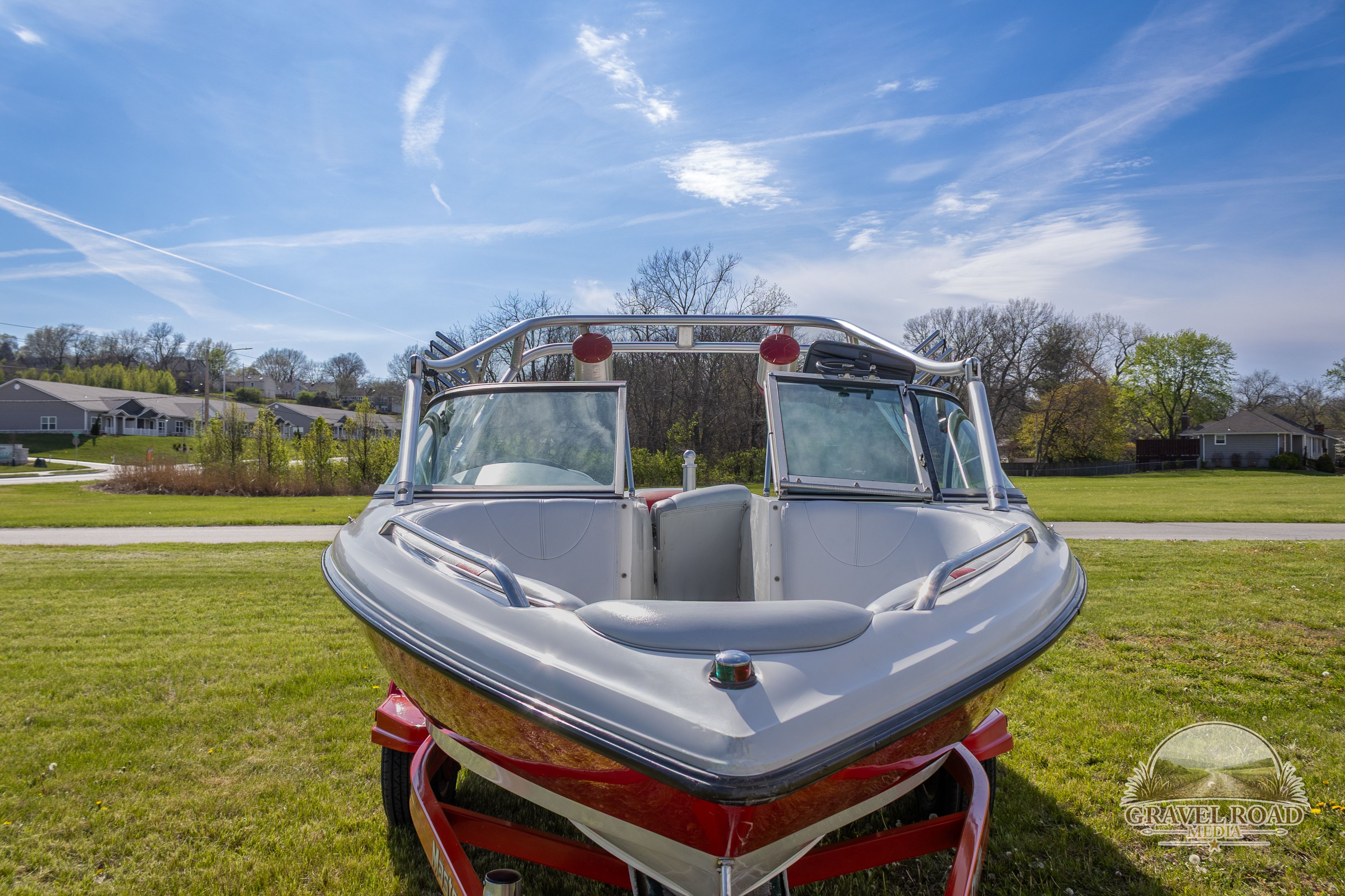 2002 MasterCraft X-7 boat on green grass under blue sky.