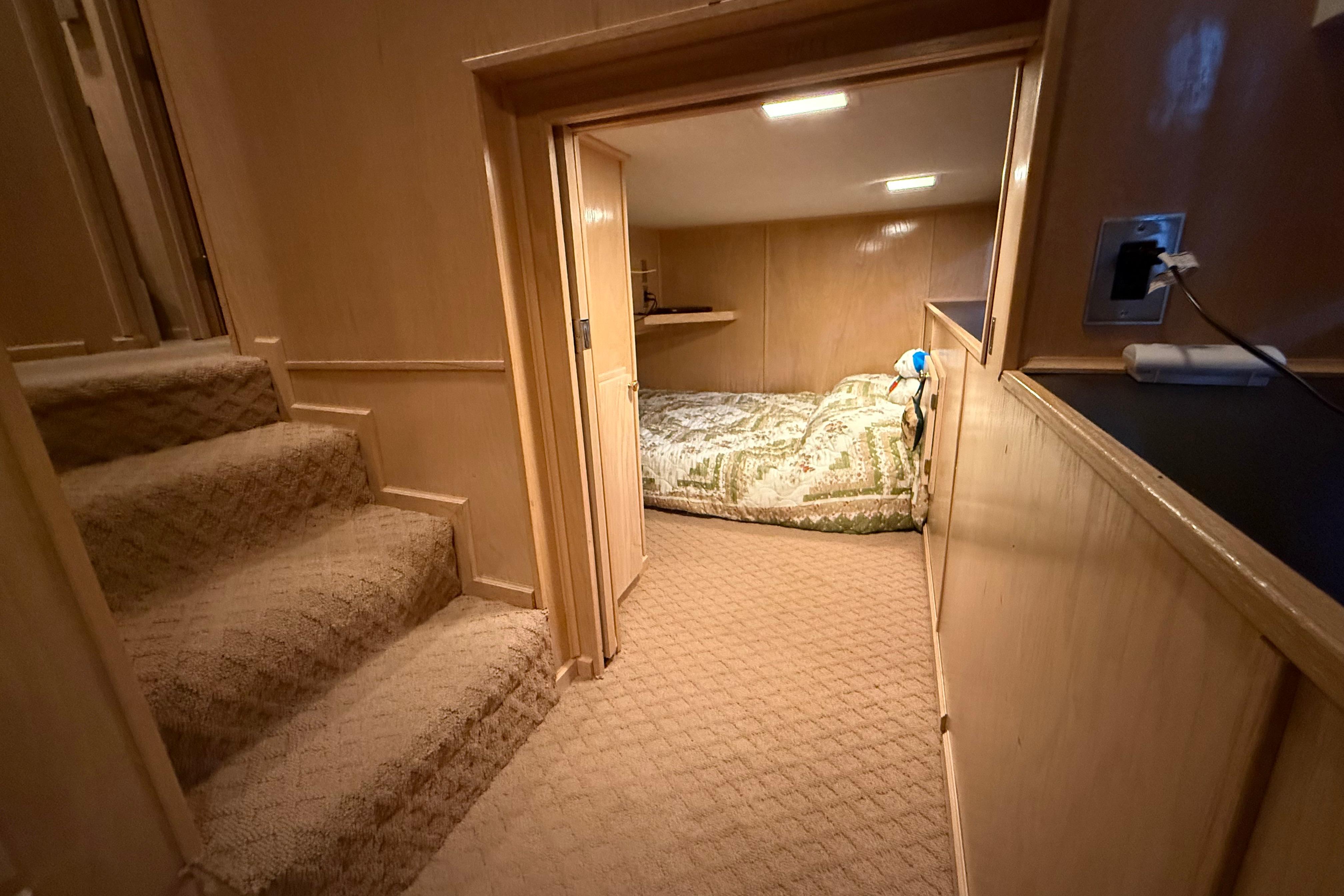 Cozy cabin interior with carpeted stairs and a small sleeping area in a 1998 Sumerset 16x76.