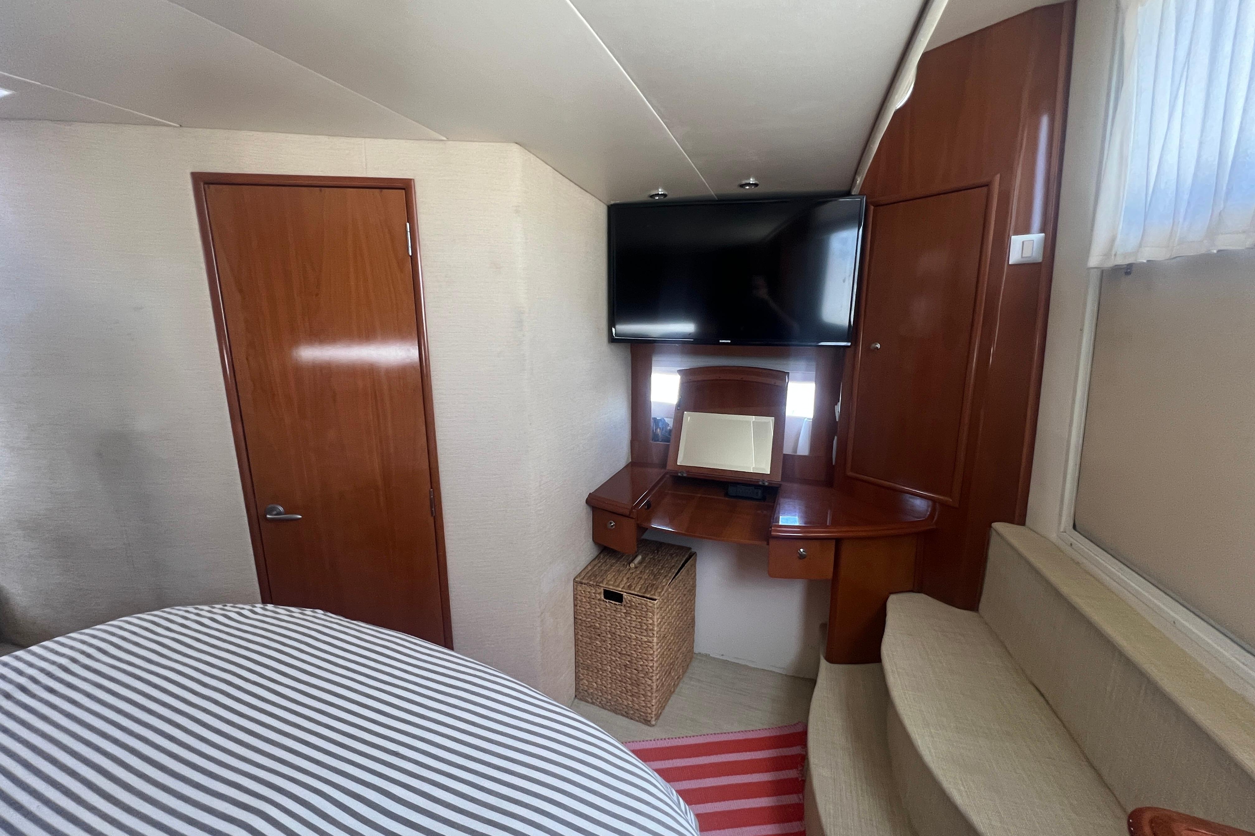 Interior of 2006 Carver 43 Motor Yacht with TV, desk, and striped bedding.