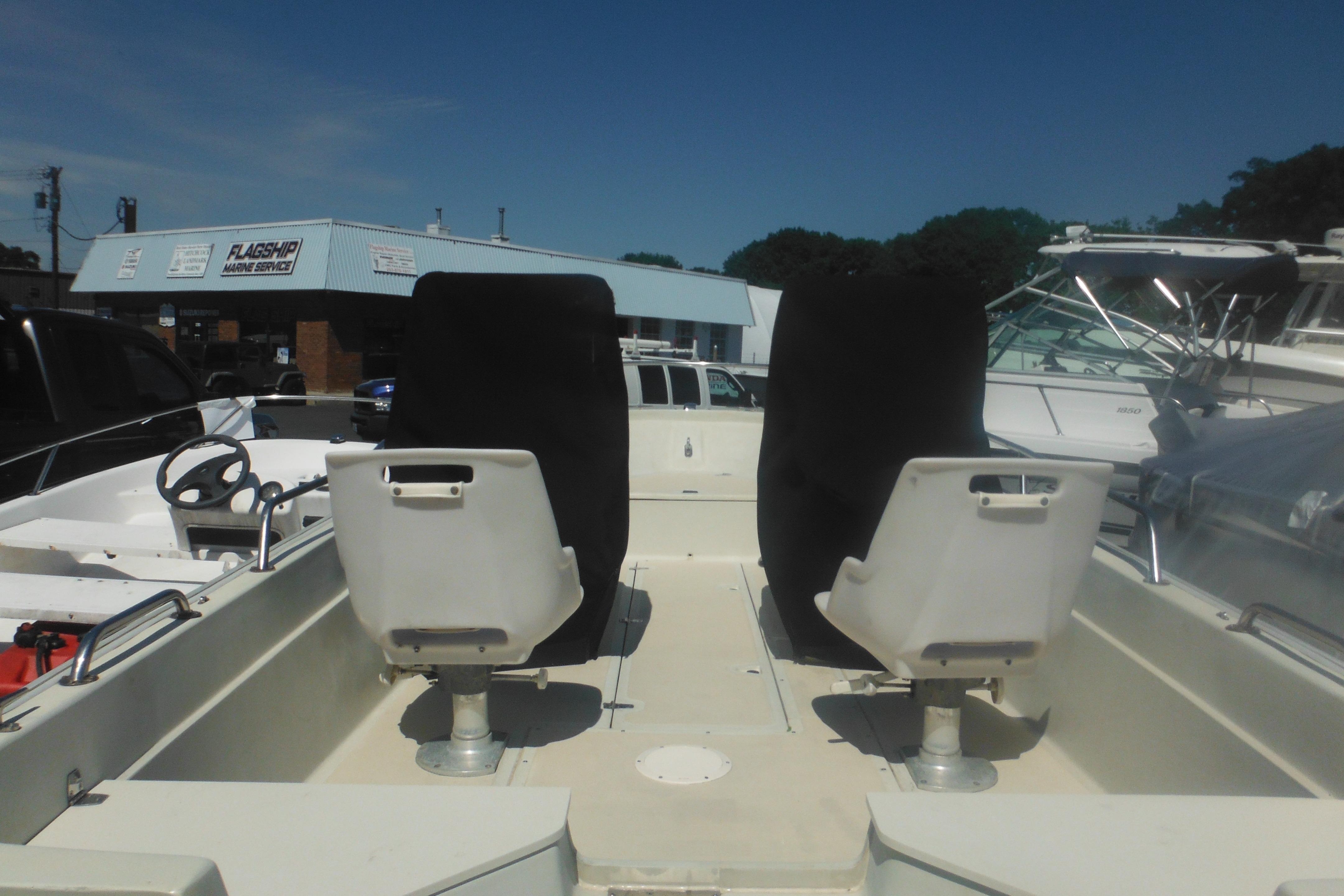 1991 Boston Whaler 16 SL boat interior with two seats, parked at a marine service center.