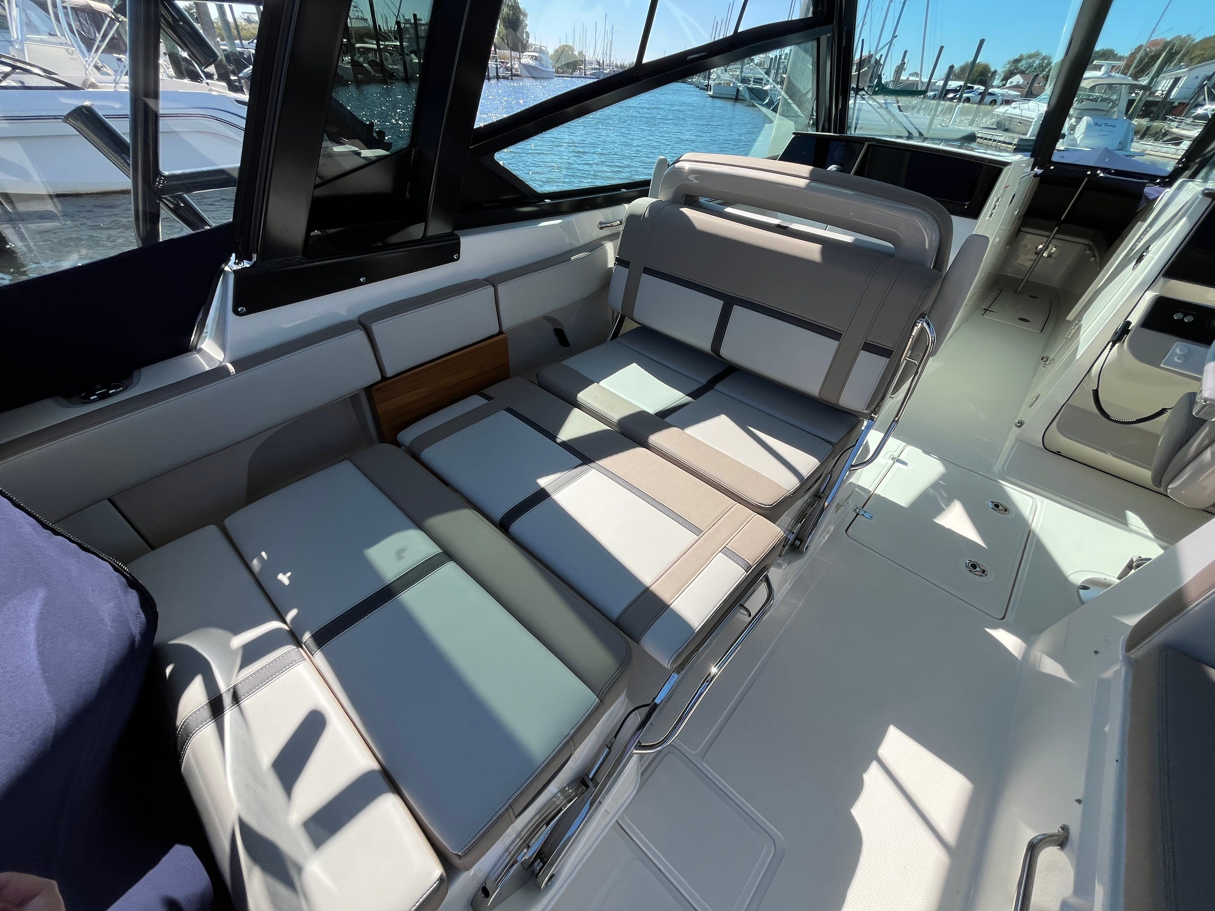 The image shows the cockpit of a Boston Whaler 330 Vantage with cushioned seats and a view of the harbor.