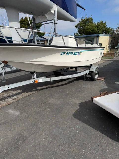 A 1992 Boston Whaler 13' jet boat on a trailer in a parking area.
