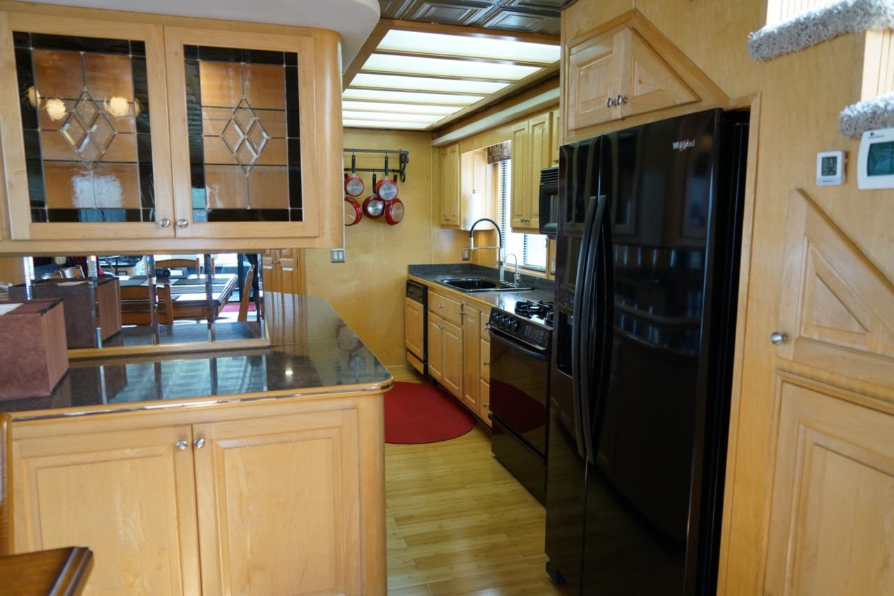 Luxurious kitchen interior of 2000 Stardust Cruisers houseboat with wooden cabinets and black appliances.