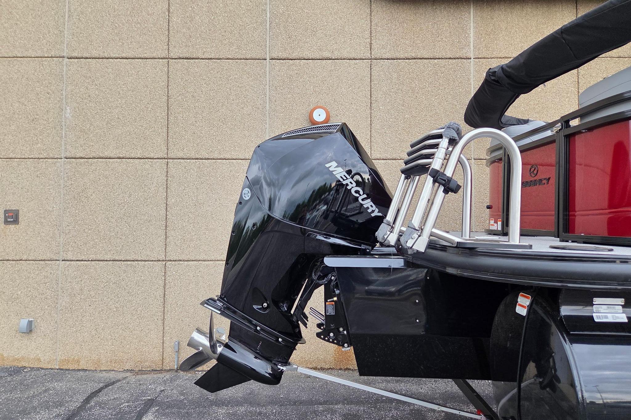 2026 Regency 230 DL boat with Mercury outboard motor, parked near a beige wall.