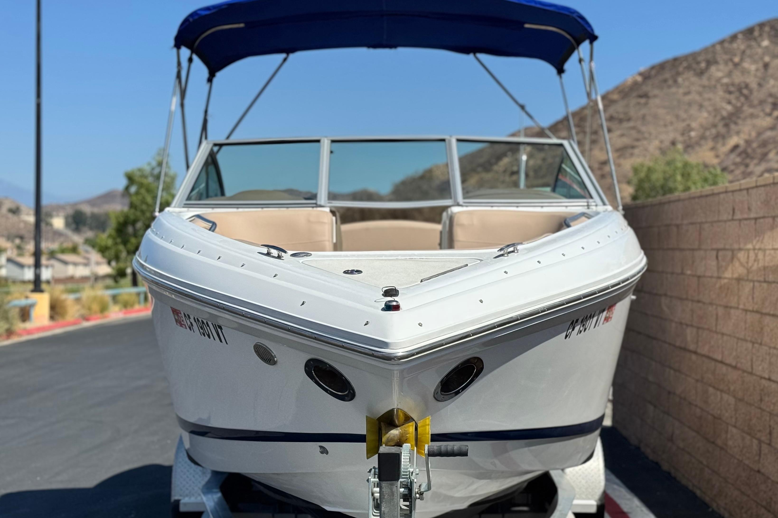 2008 Cobalt 262 boat with blue canopy, parked on a trailer, mountain background.