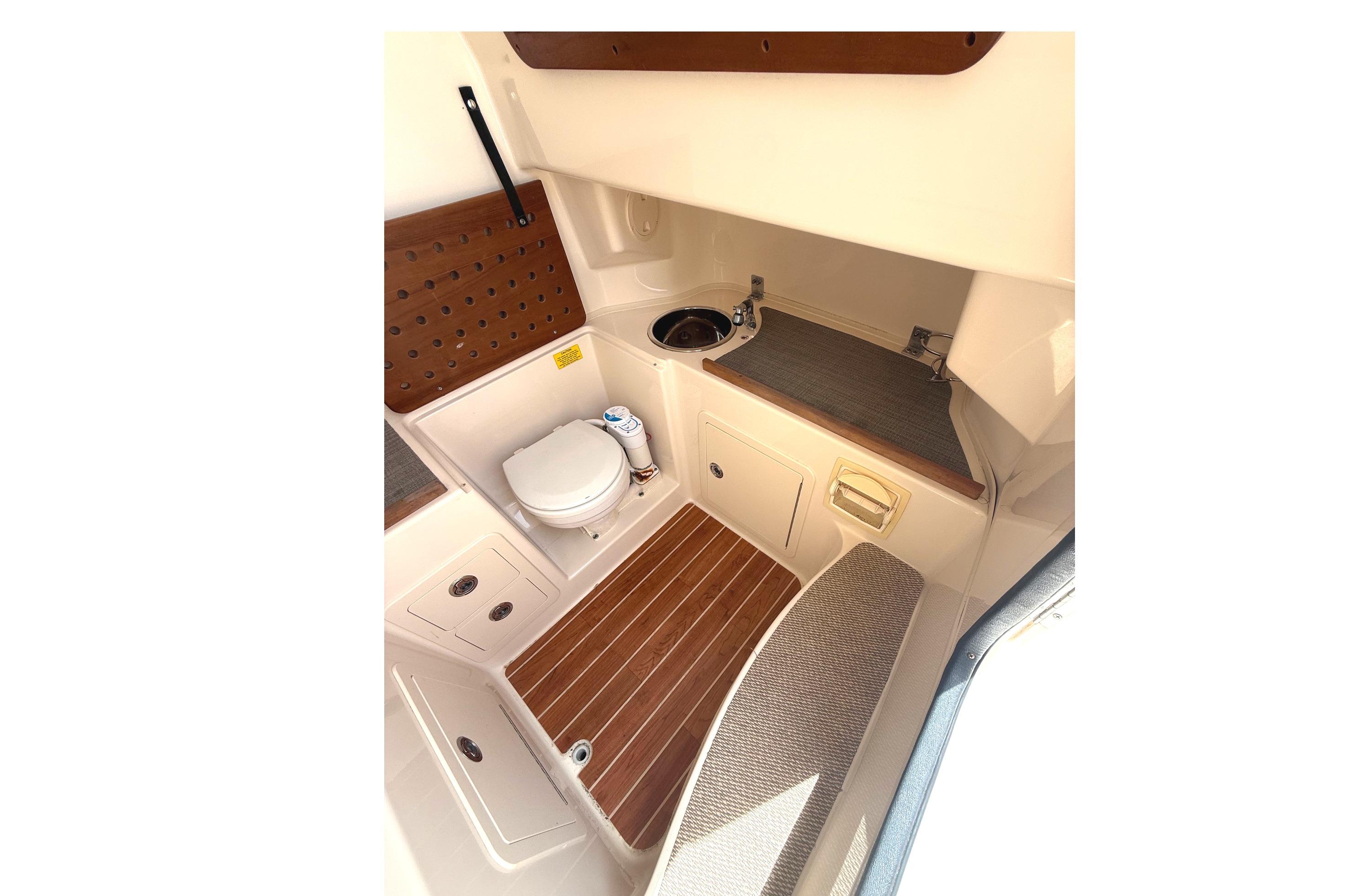 2018 Grady-White Canyon 306 boat interior with toilet, sink, and wooden flooring.