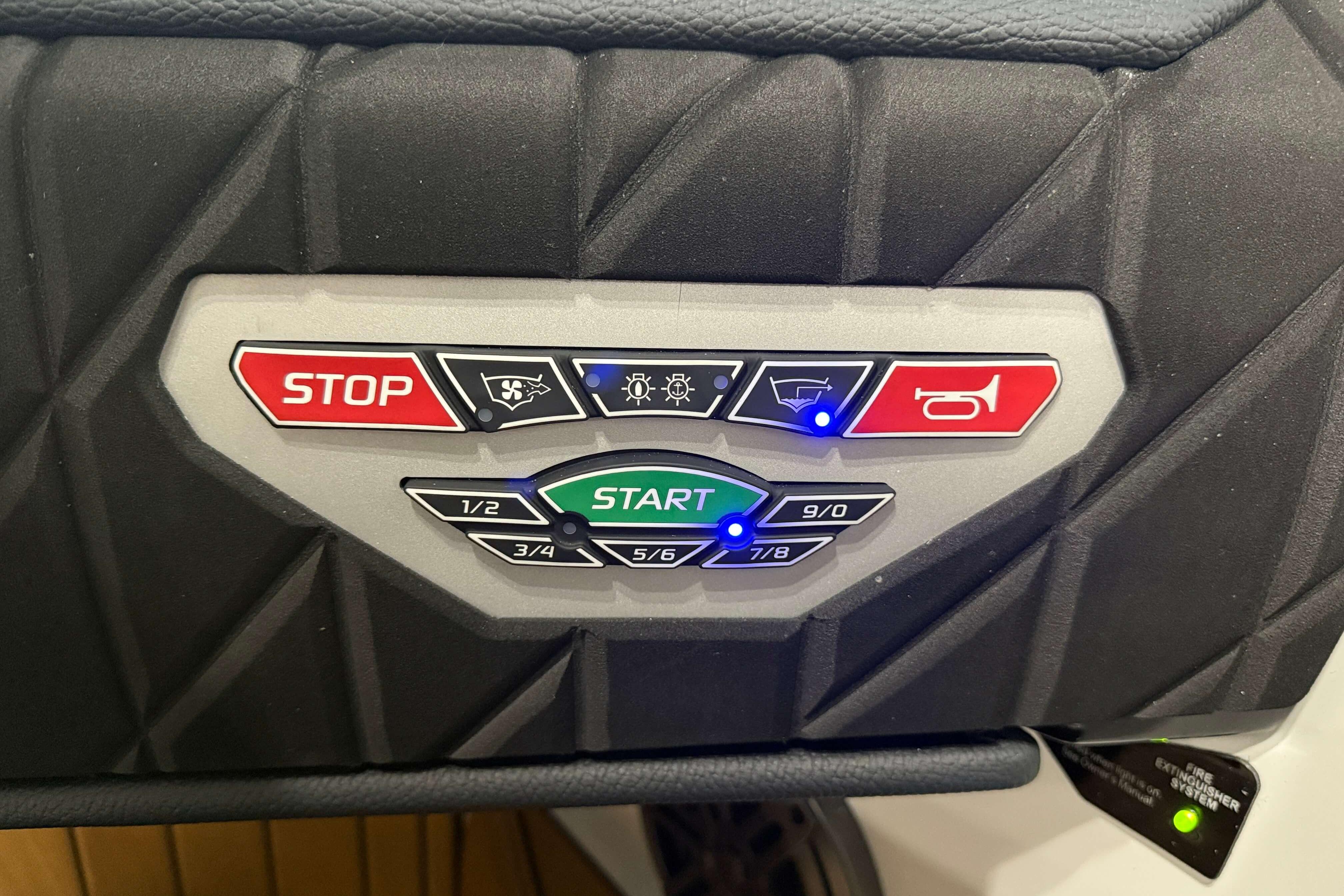 Control panel of 2026 Nautique Super Air Nautique S23 boat with start and stop buttons.