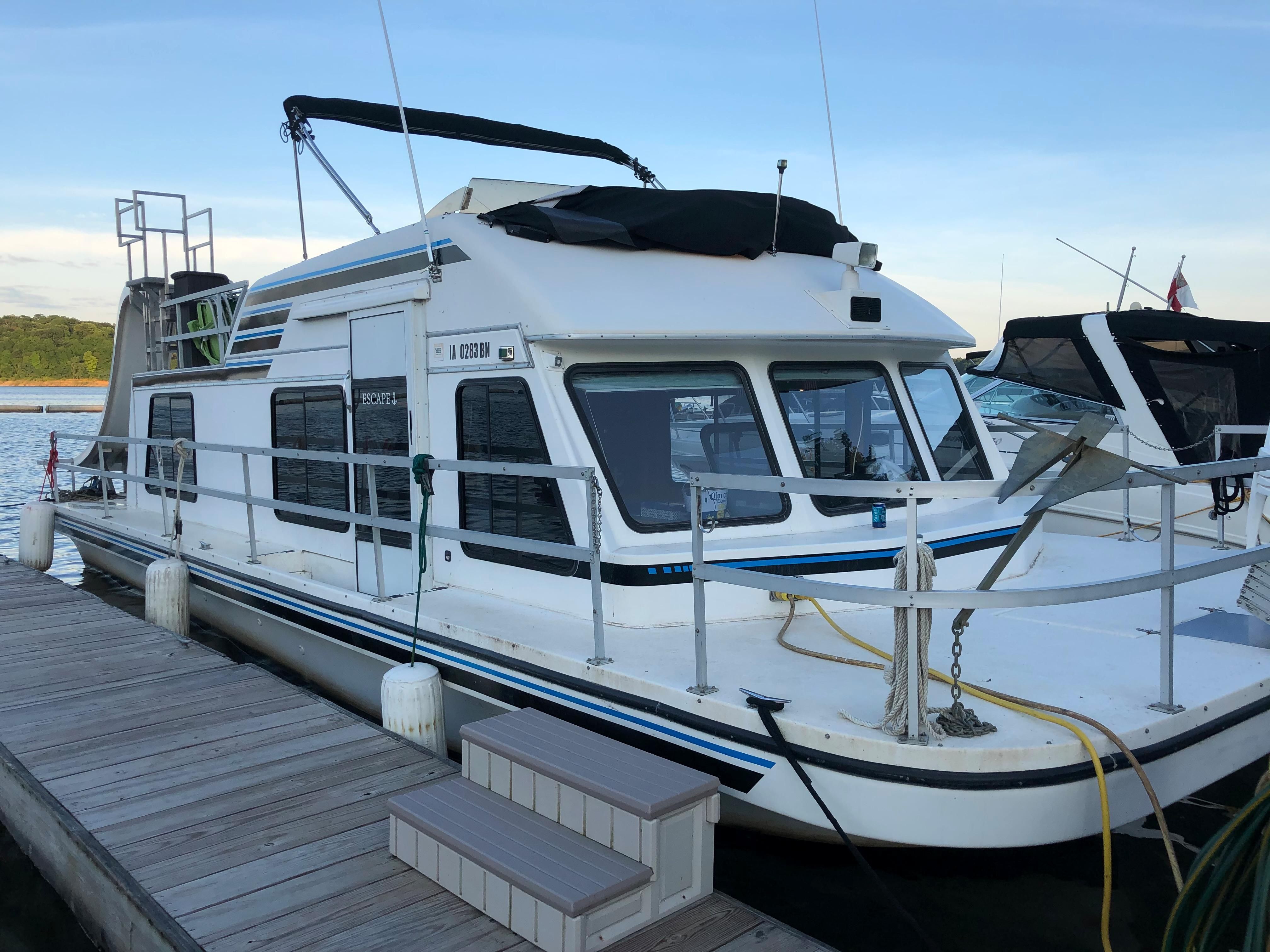 A 1993 Gibson Sport Series houseboat docked. It features a spacious deck.