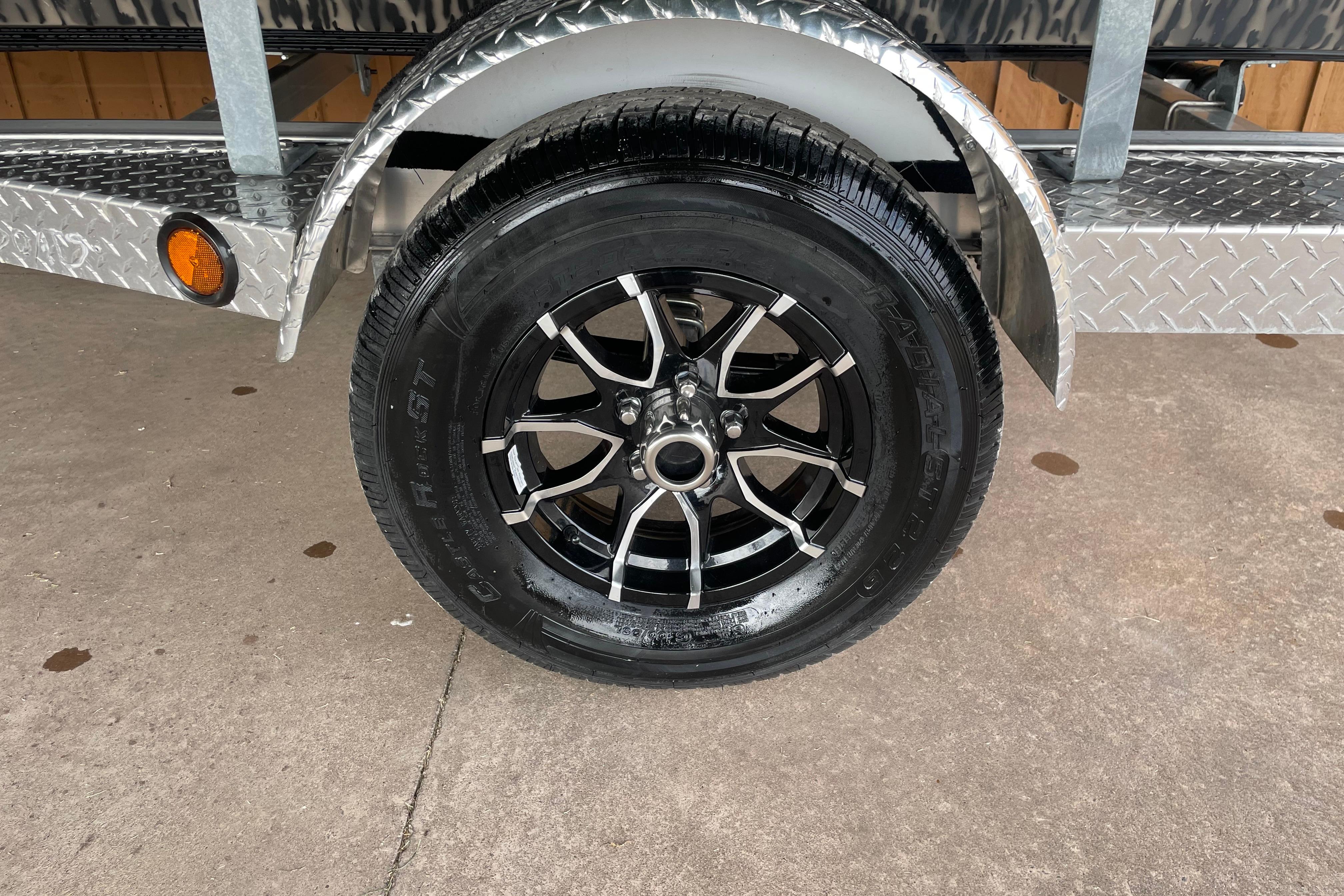 Trailer wheel of 2026 Reaper Boats 753 Timber Reaper, featuring sleek black alloy rims.