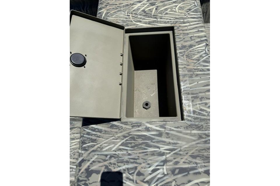 Open storage compartment in 2026 Tracker Grizzly 15 Jon boat with camouflage pattern.