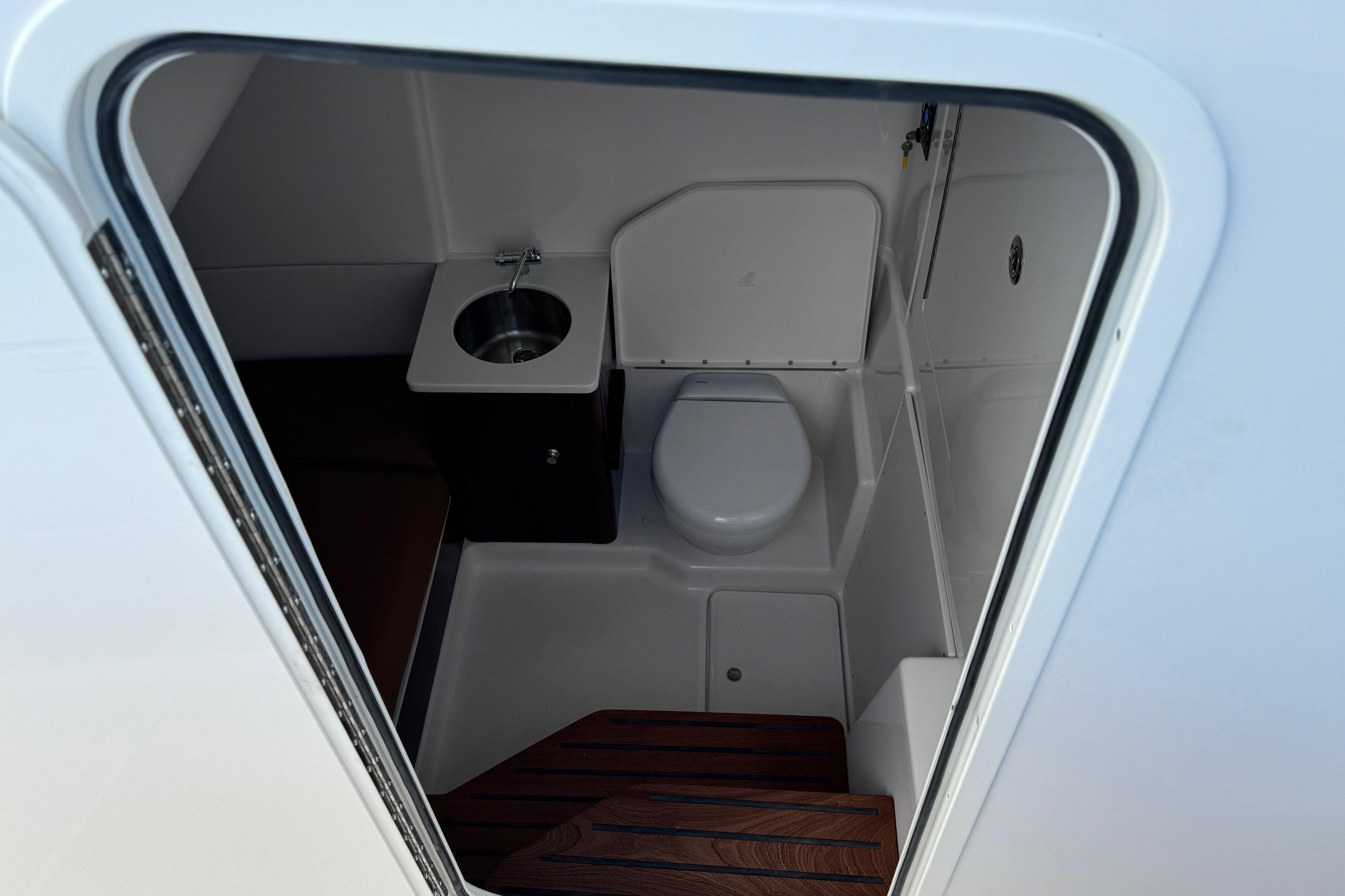 2025 Robalo R360 Center Console boat interior with compact bathroom and sink.