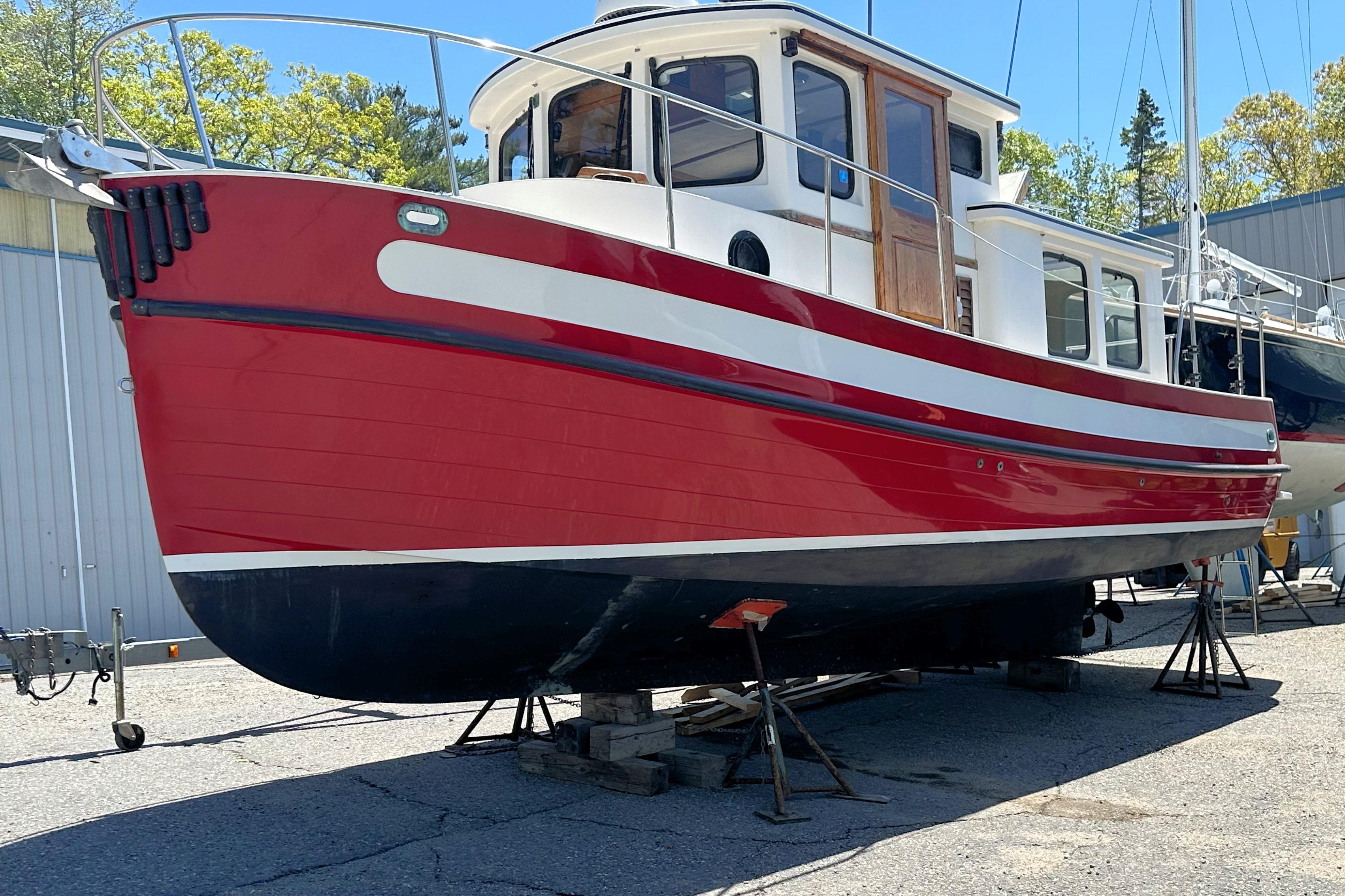 1985 Nordic Tug 26 boat with red and white hull, docked on land.