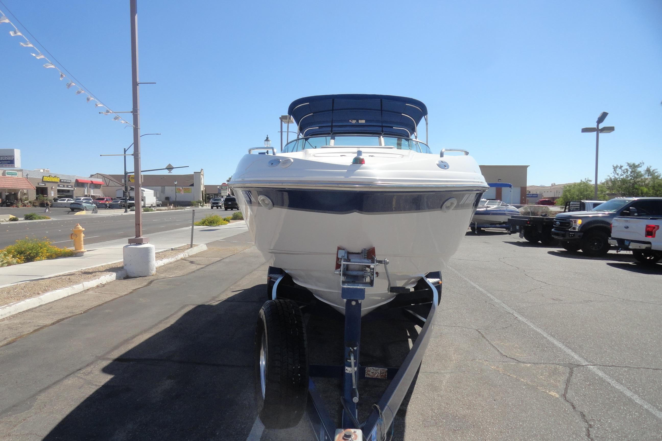 2001 Chaparral 265 SSi boat on trailer, parked in a sunny urban area.