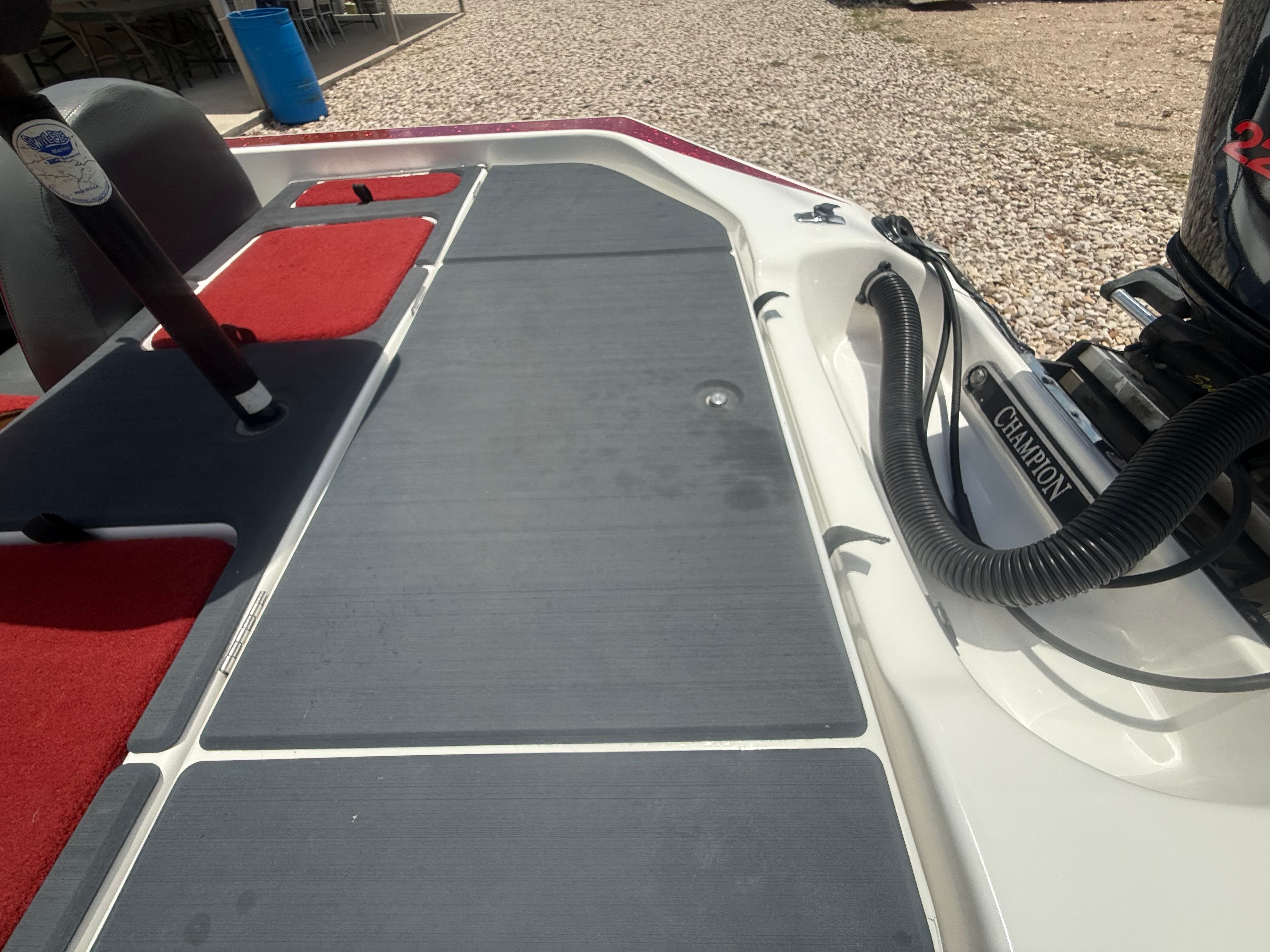 The image shows the deck of a 1999 Champion 202 boat with red and gray upholstery.
