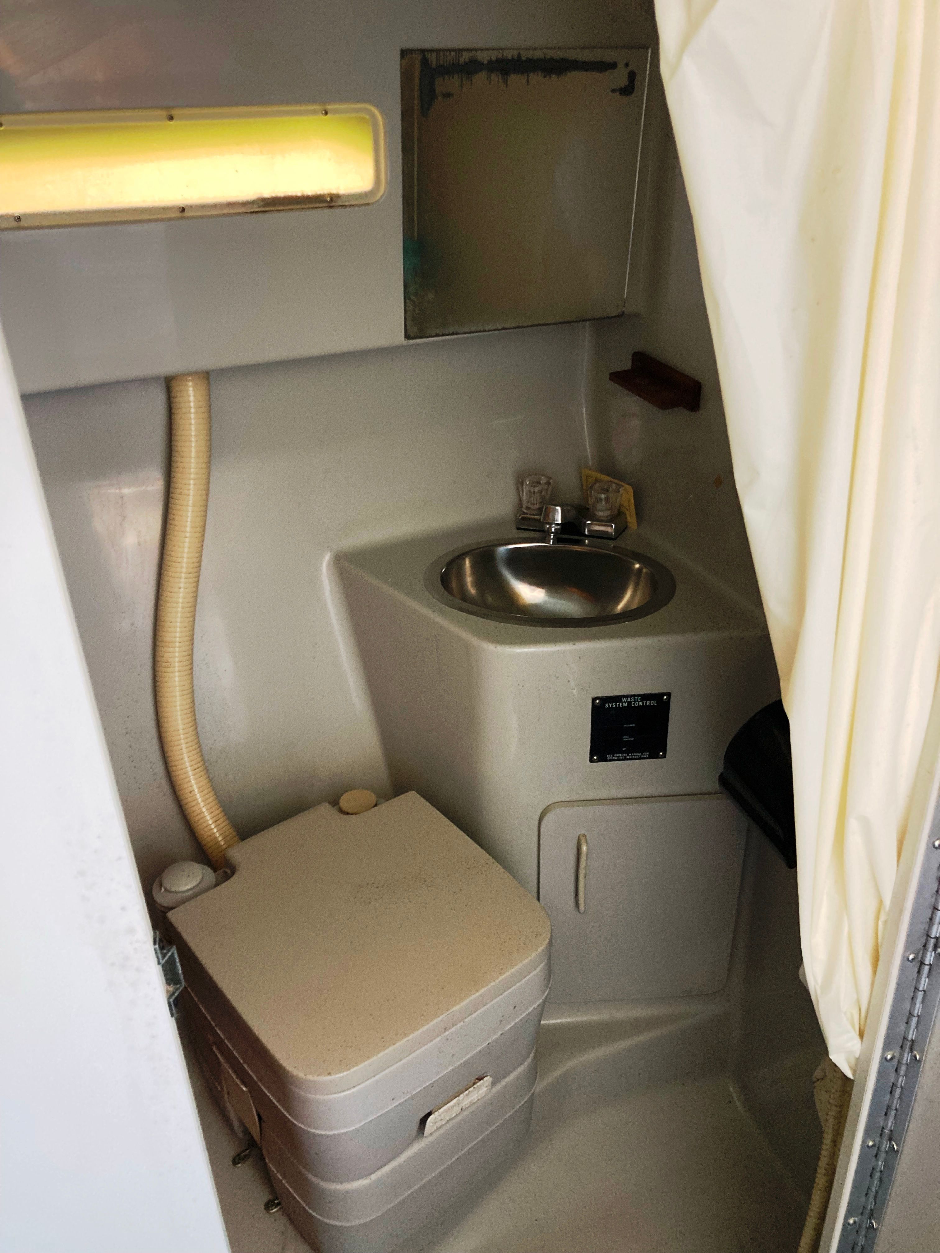 The image shows a small boat bathroom with a sink and portable toilet.