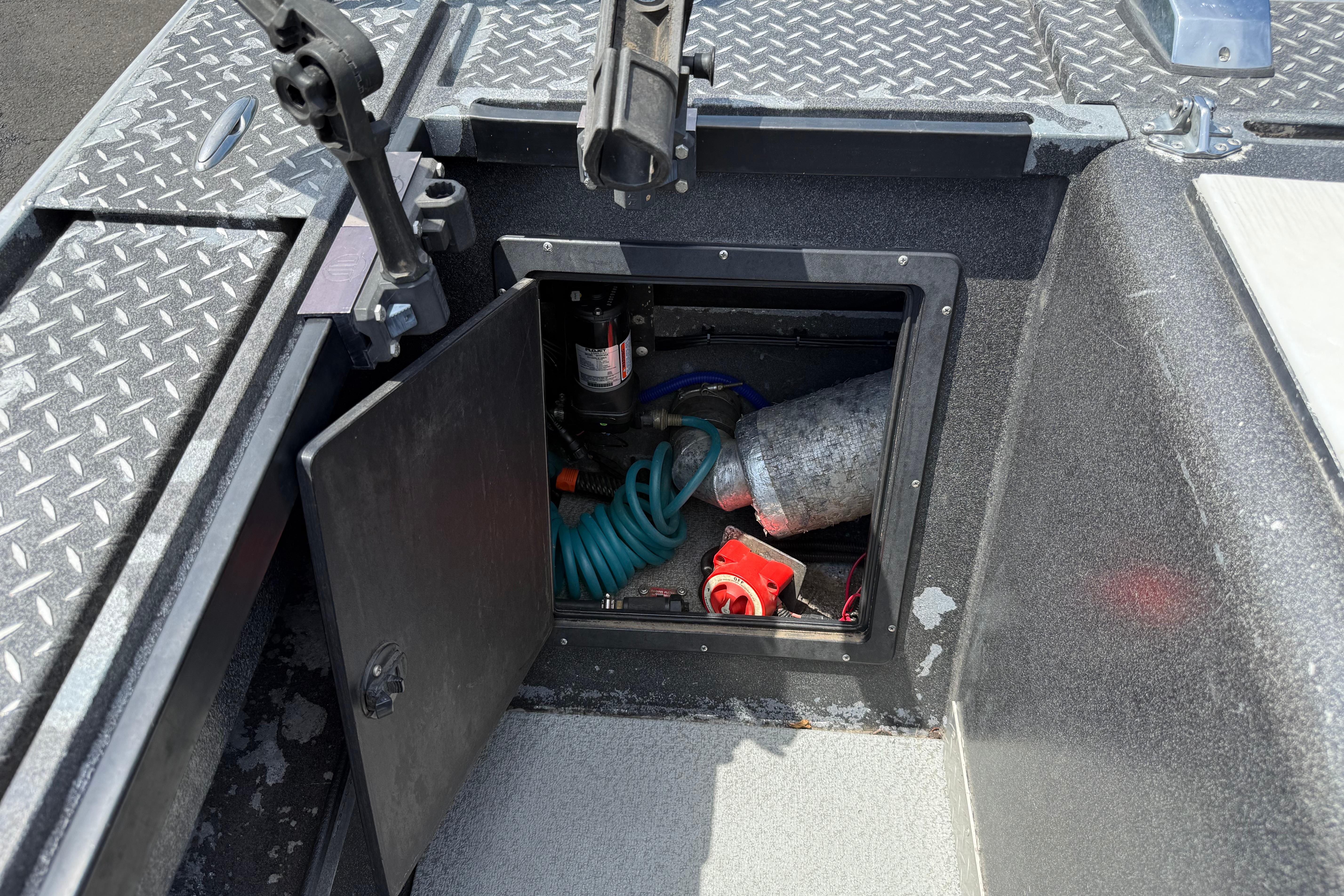 Open storage compartment on a 2005 Willie Raptor 21' boat with various equipment inside.