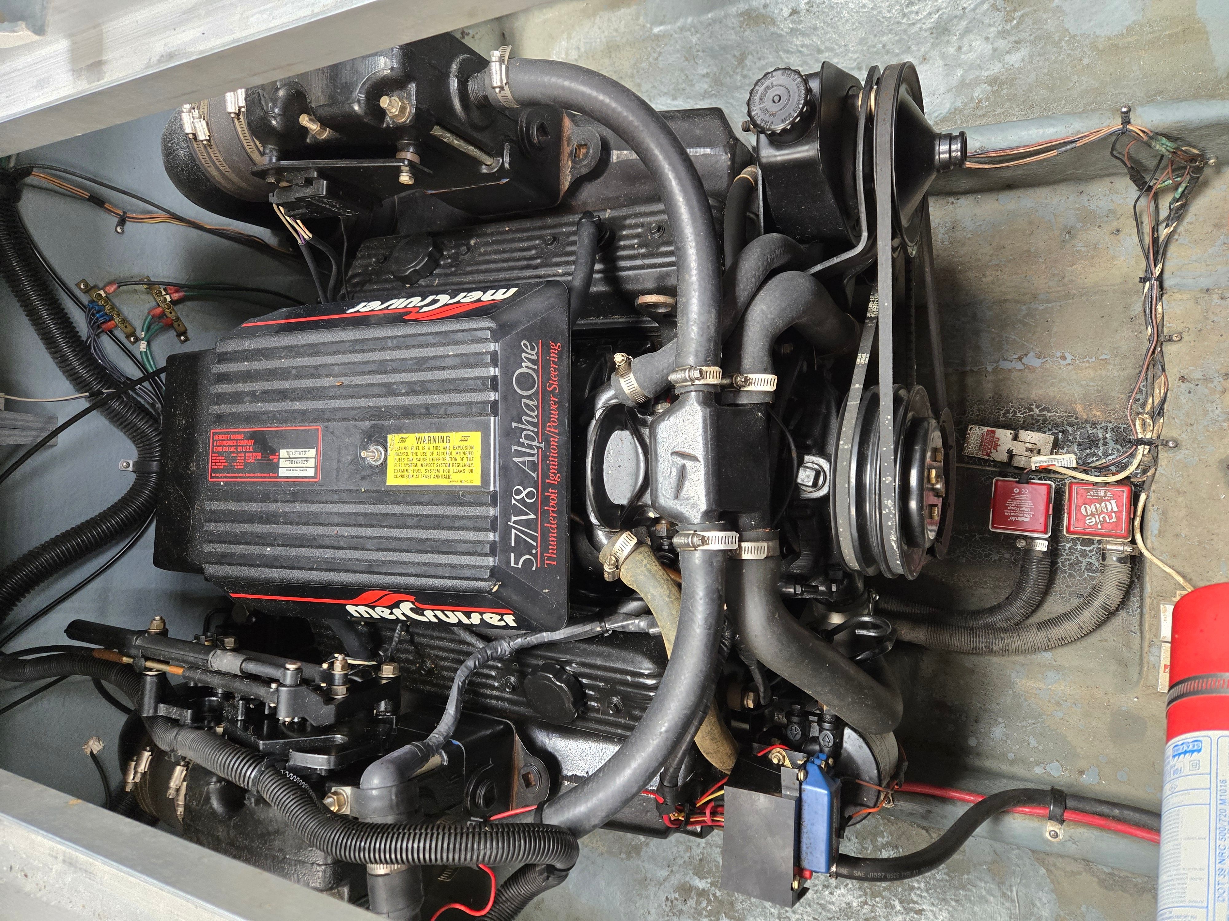 An engine compartment with a MerCruiser 5.7L V8 Alpha One engine, surrounded by cables and hoses.