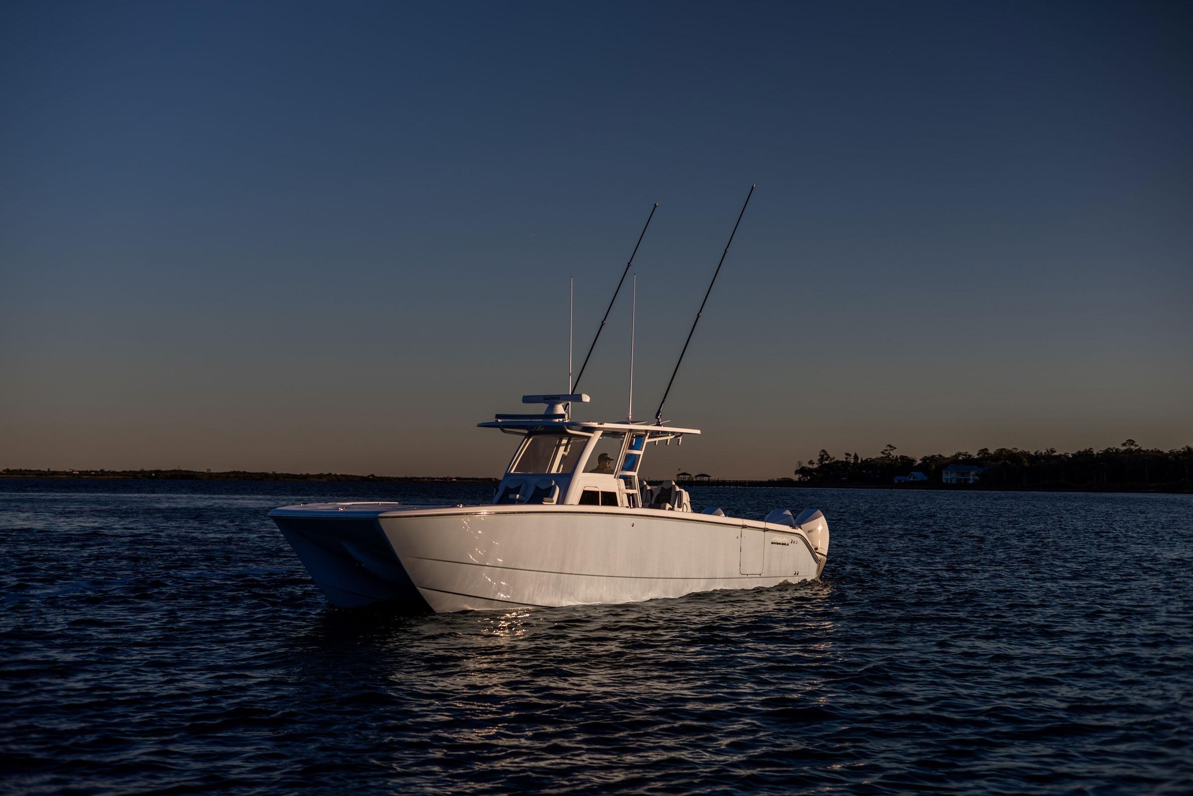 2025 Invincible 38 Catamaran on calm water at sunset.