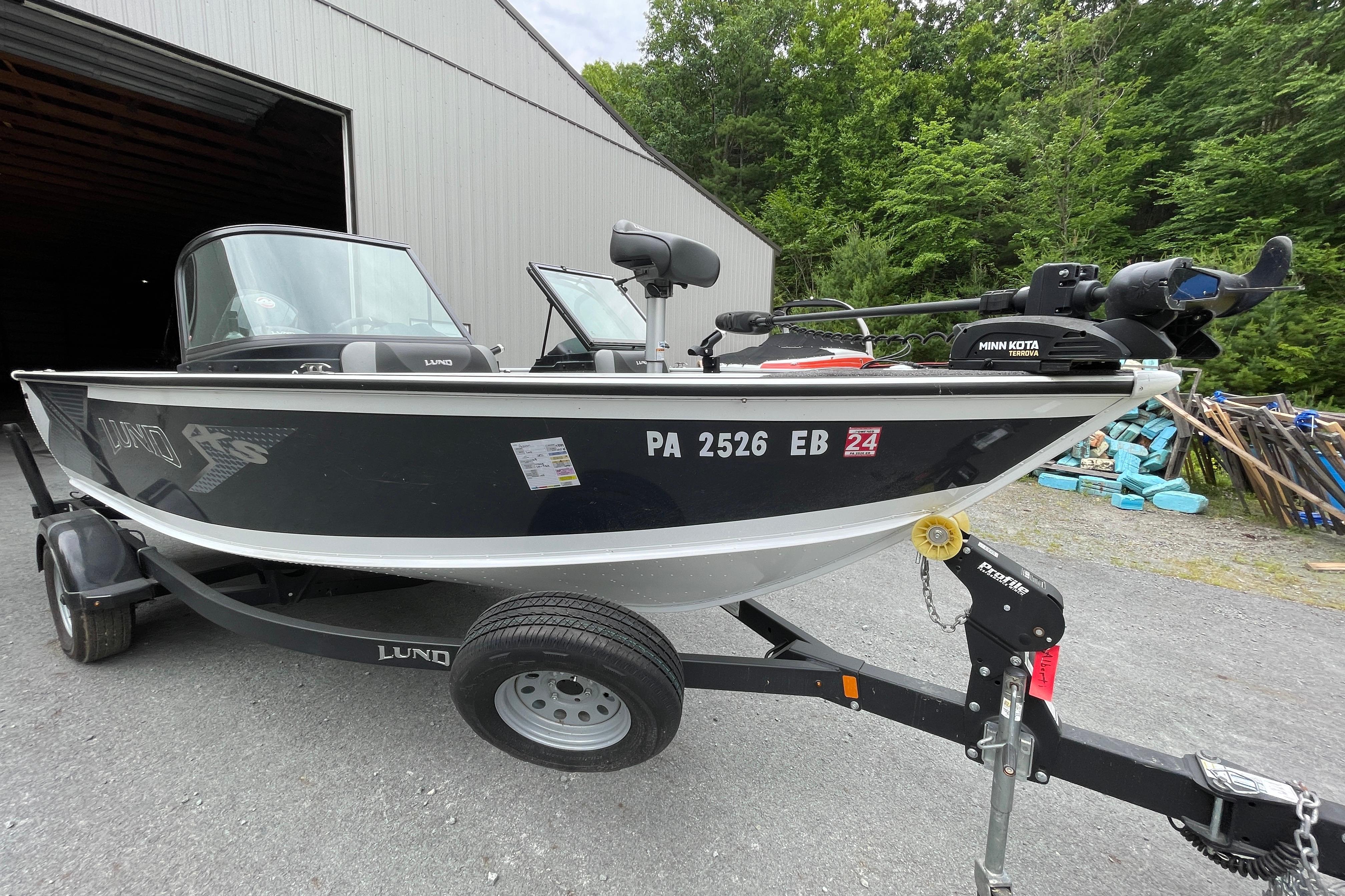 2022 Lund 1875 Crossover XS boat on trailer, parked near a building.