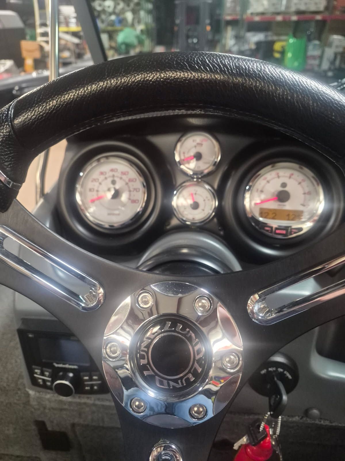 Close-up of a Lund Pro-V 2075 boat's helm with gauges and steering wheel.