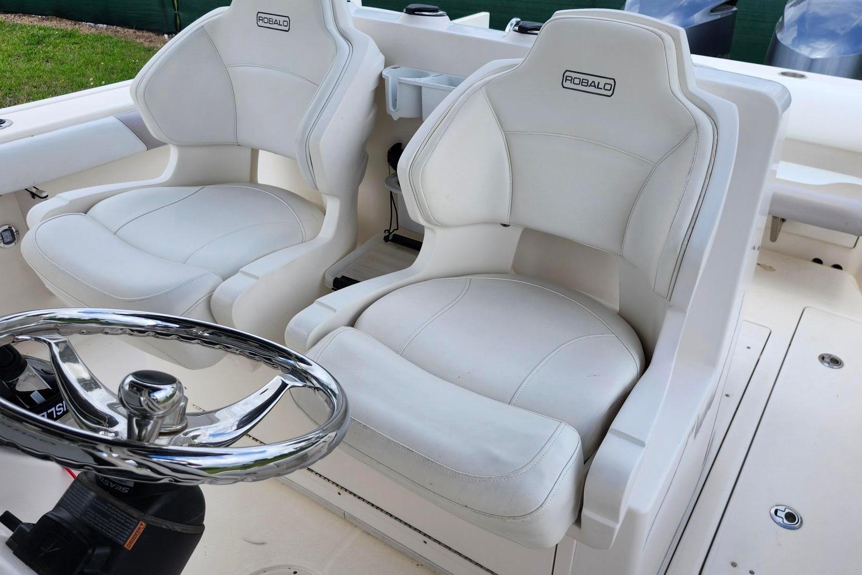 2015 Robalo R300 Center Console boat with white cushioned seats and steering wheel.