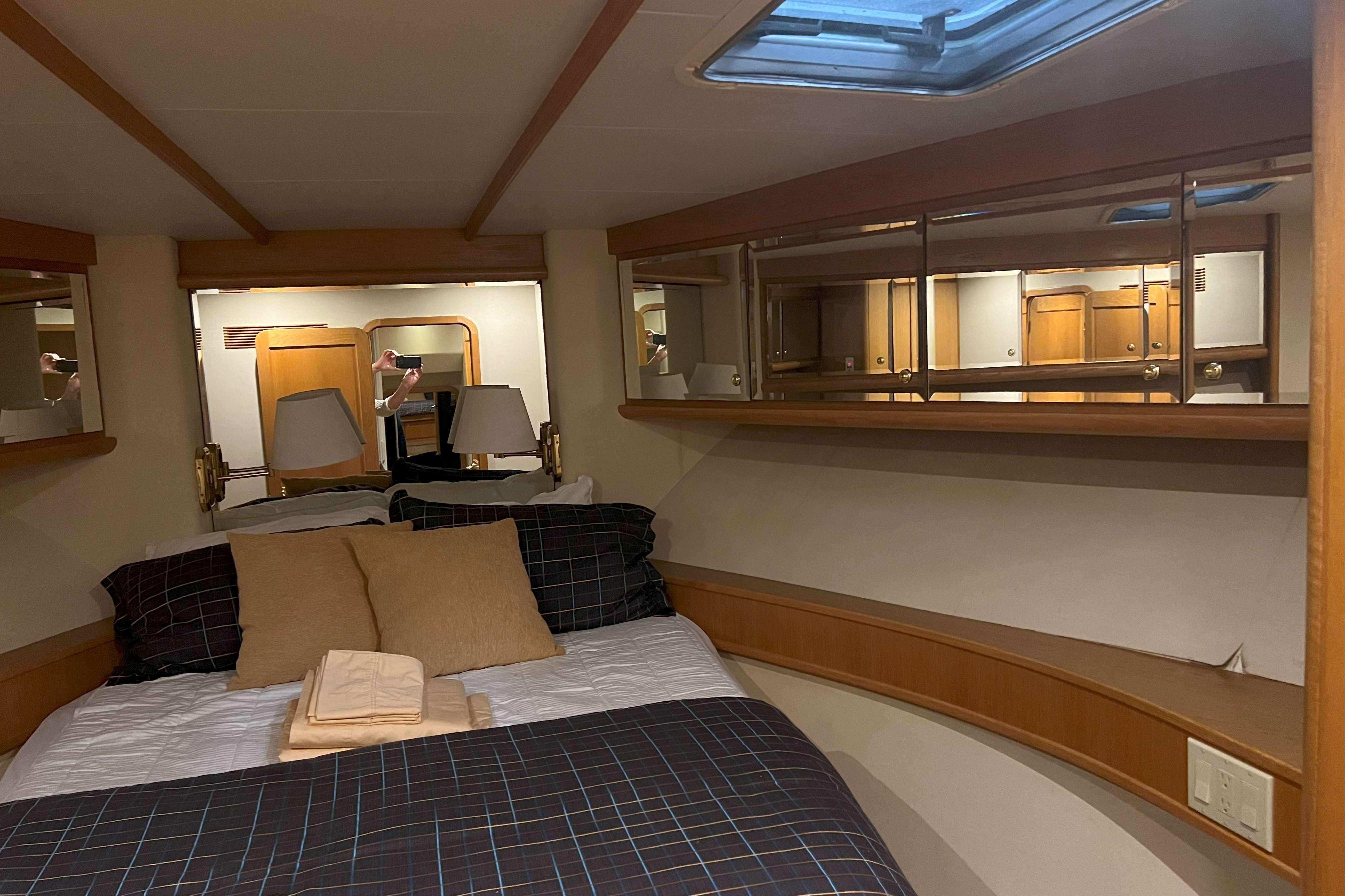Cozy bedroom interior of 1998 West Bay 58 yacht with skylight and mirrors.