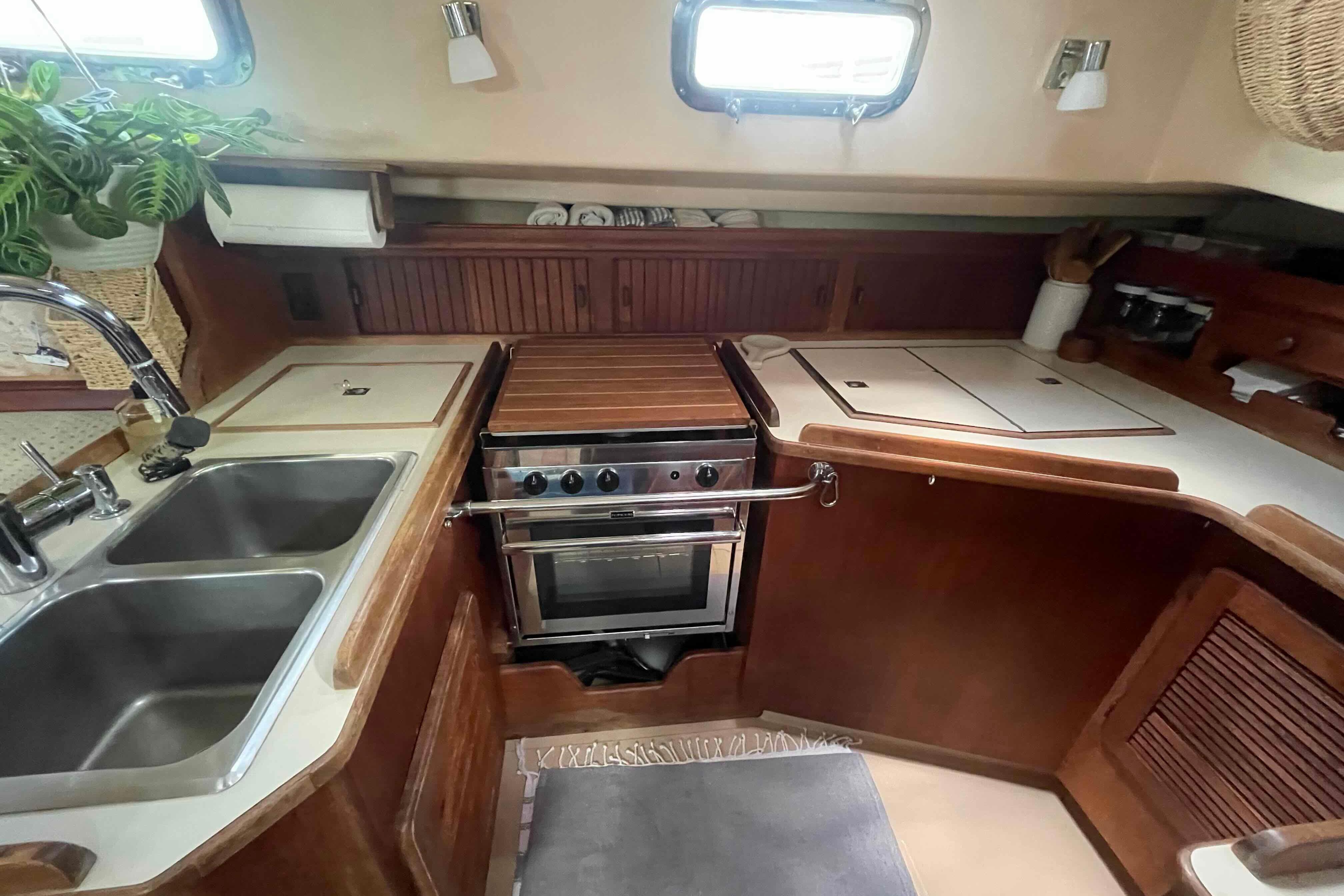 1989 Island Packet 35 yacht kitchen with stove, sink, and wooden cabinetry.
