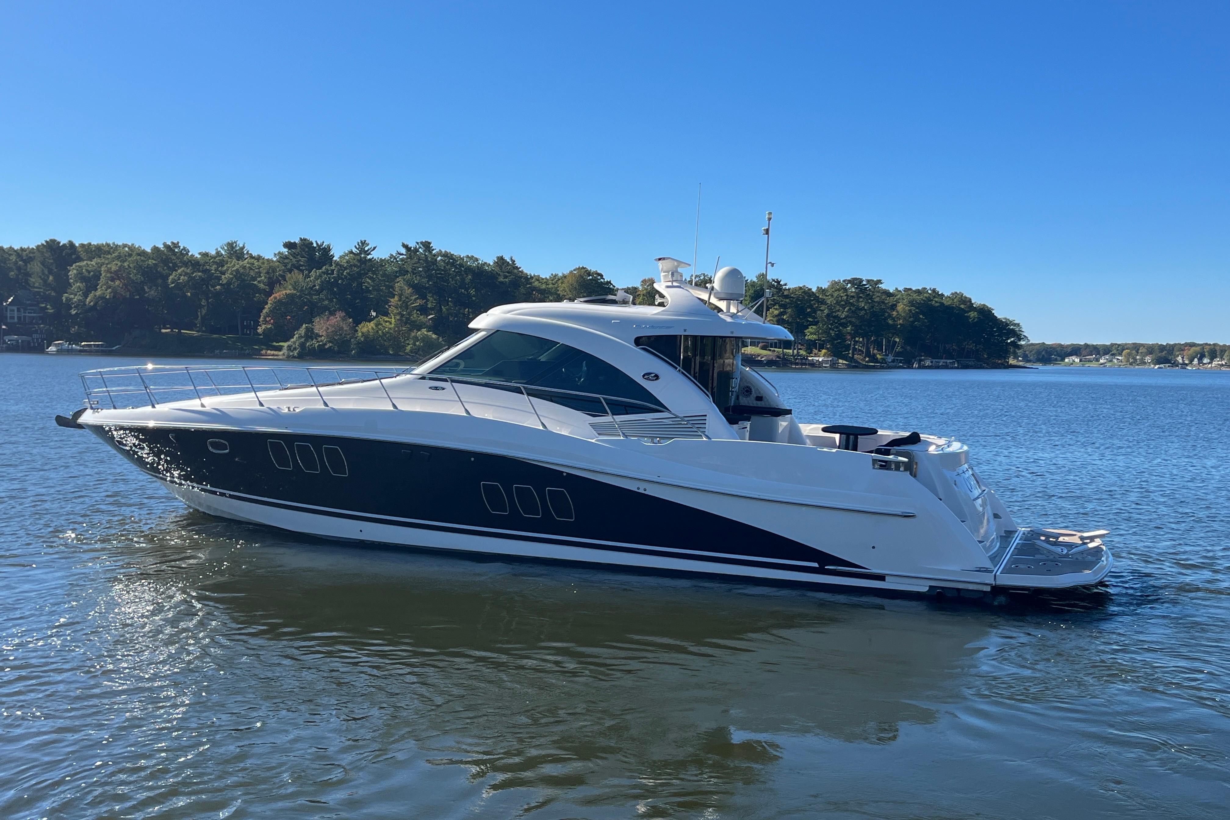 2007 Sea Ray 60 Sundancer yacht cruising on a serene lake under a clear blue sky.